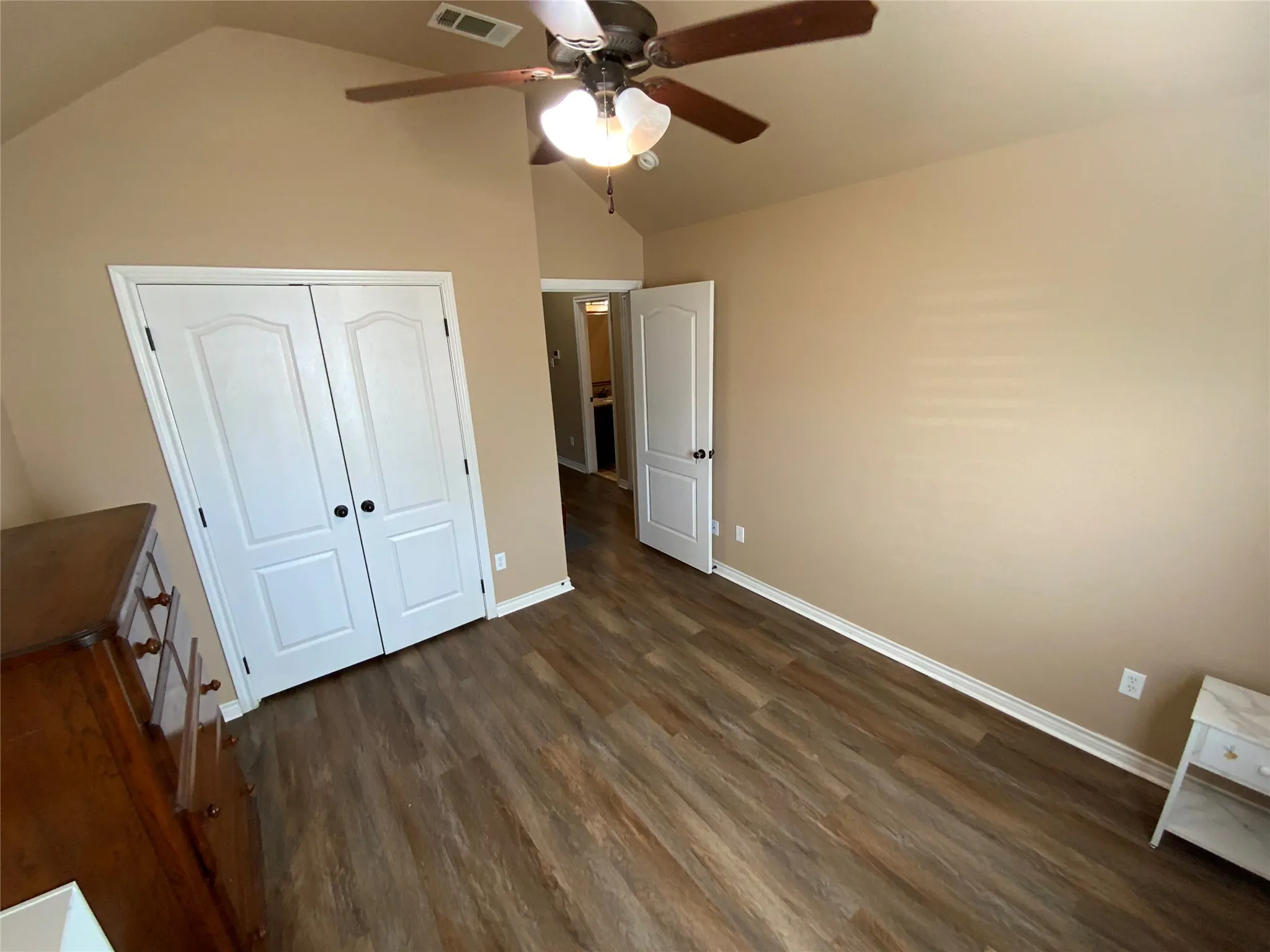 Vaulted ceiling with a ceiling fan, wood-finish flooring, and white paneled doors