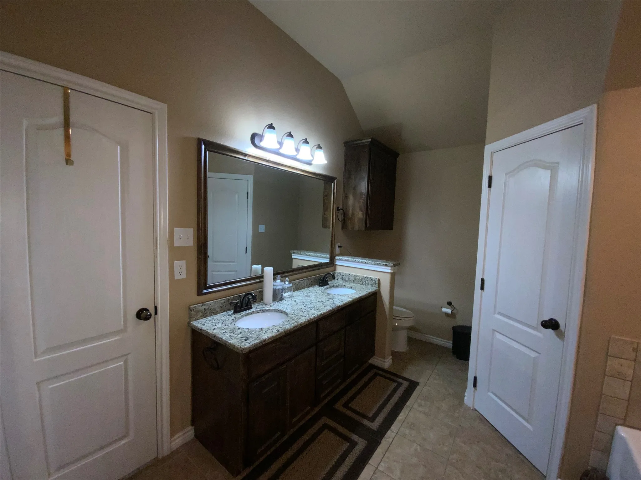Dual vanity with granite-style countertop, undermount sinks, and dark wood-finish cabinetry