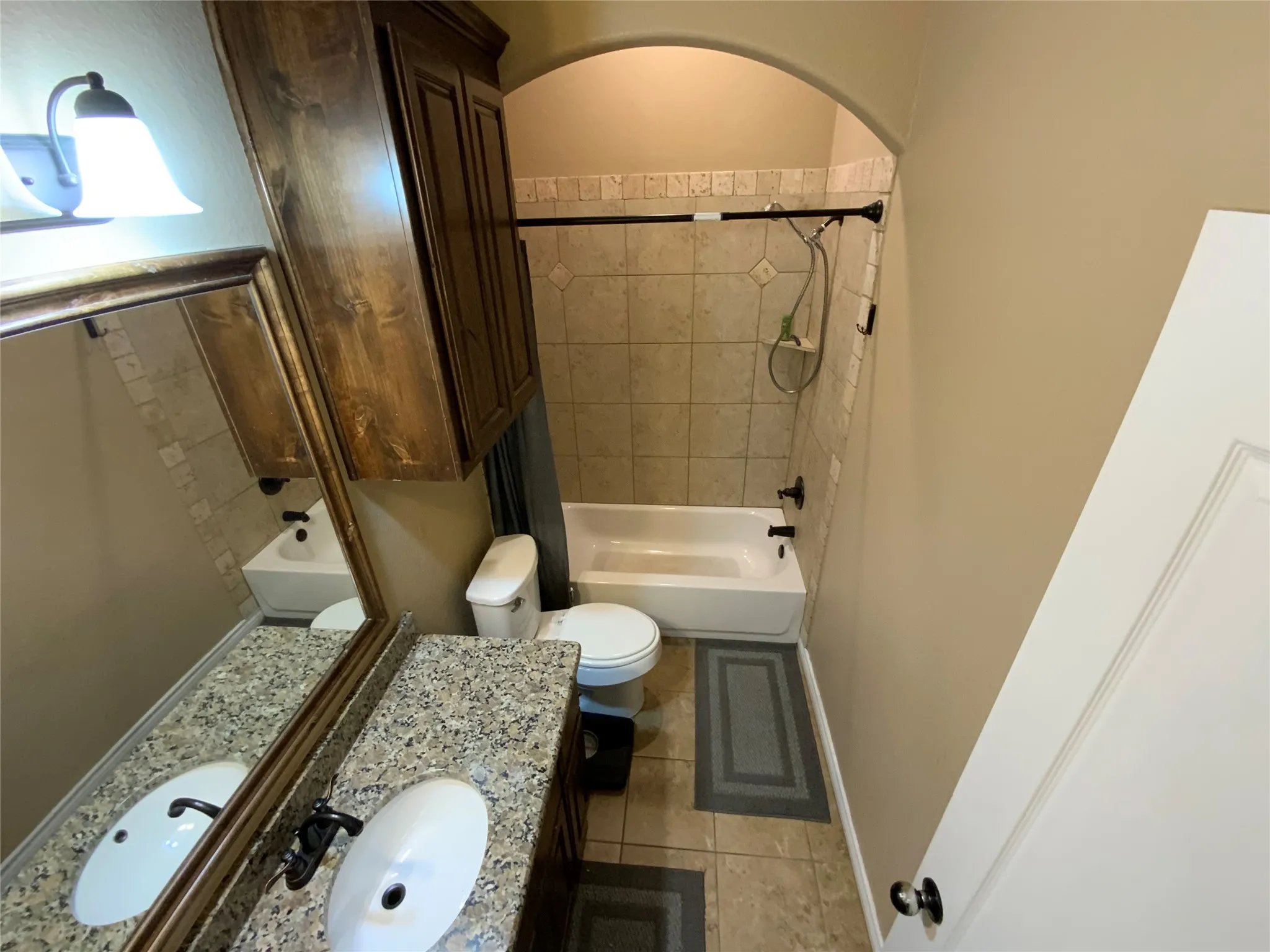 Dual vanity with an integrated sink, granite-style countertop, and wood-finish cabinetry