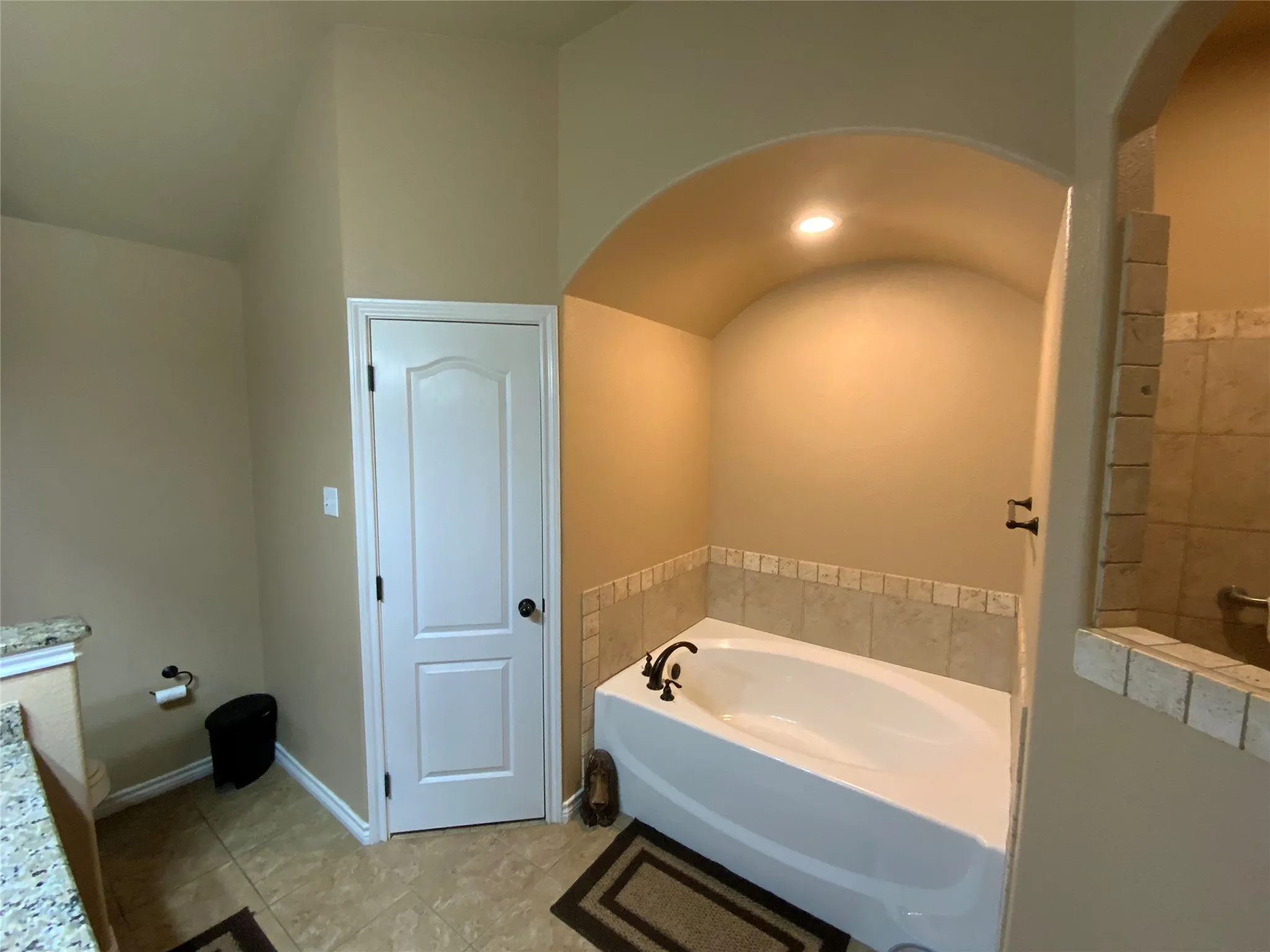 Built-in soaking tub with dark bronze fixtures and a tiled surround