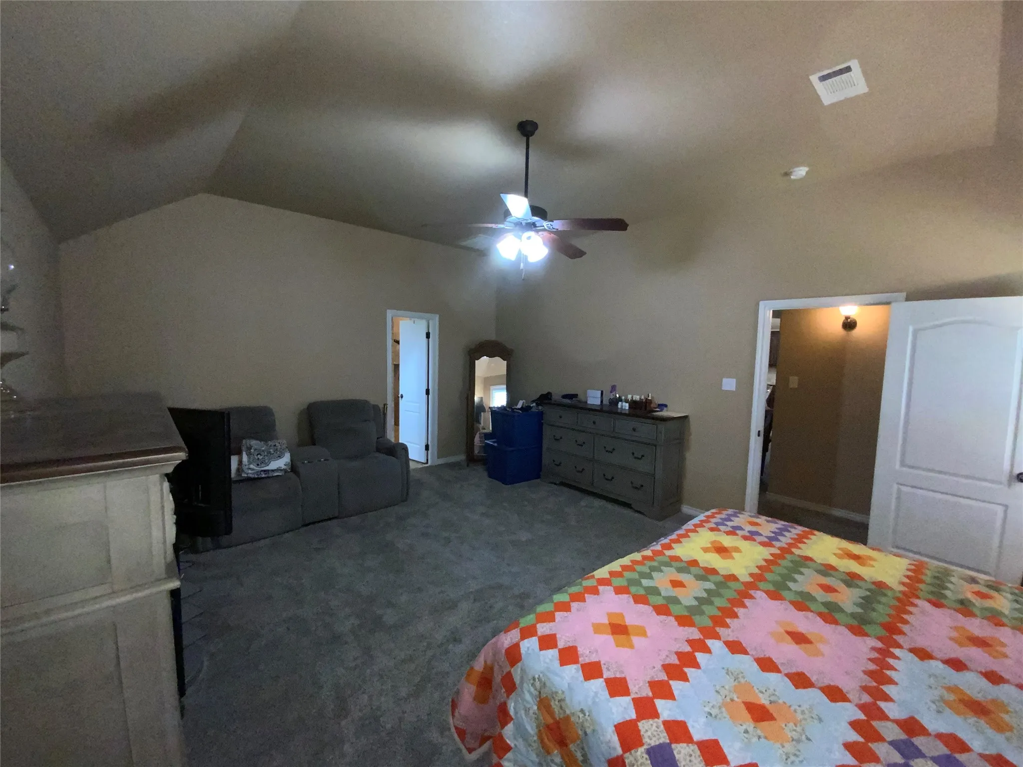 Vaulted ceiling with a ceiling fan, carpeted flooring, and a paneled interior door