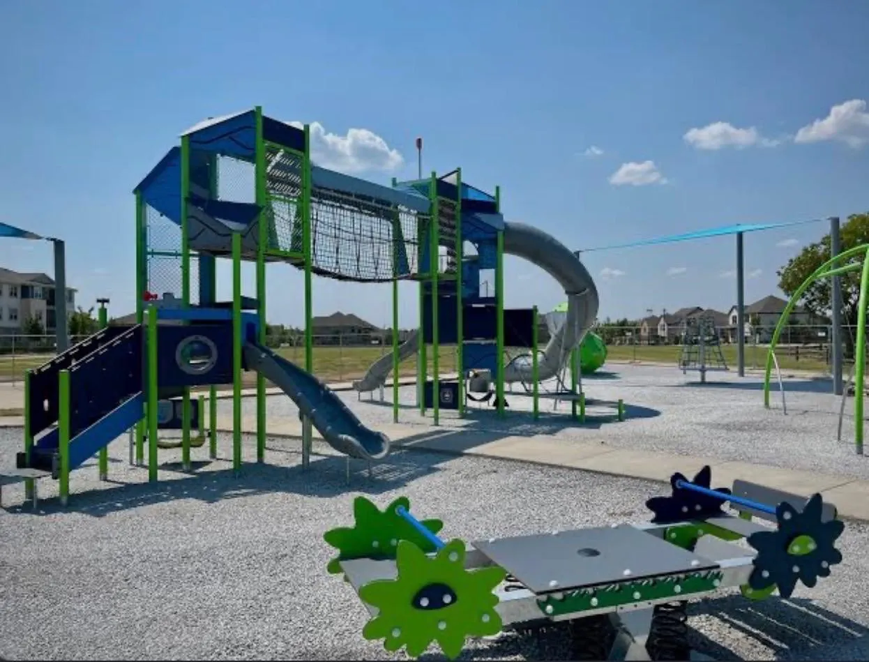 Outdoor play area featuring a multi-level play structure, tube slide, open slide, and a spring rider