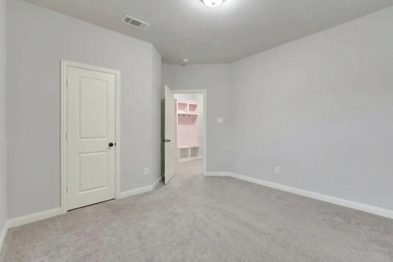 Light gray wall paint, gray carpeting, white interior doors, built-in shelving, and a ceiling-mounted light fixture