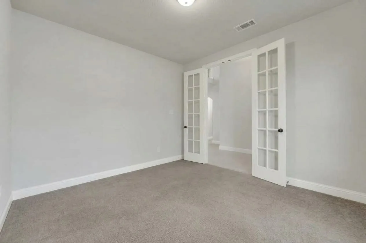 Light gray wall paint, gray carpet, white trim, and double French doors