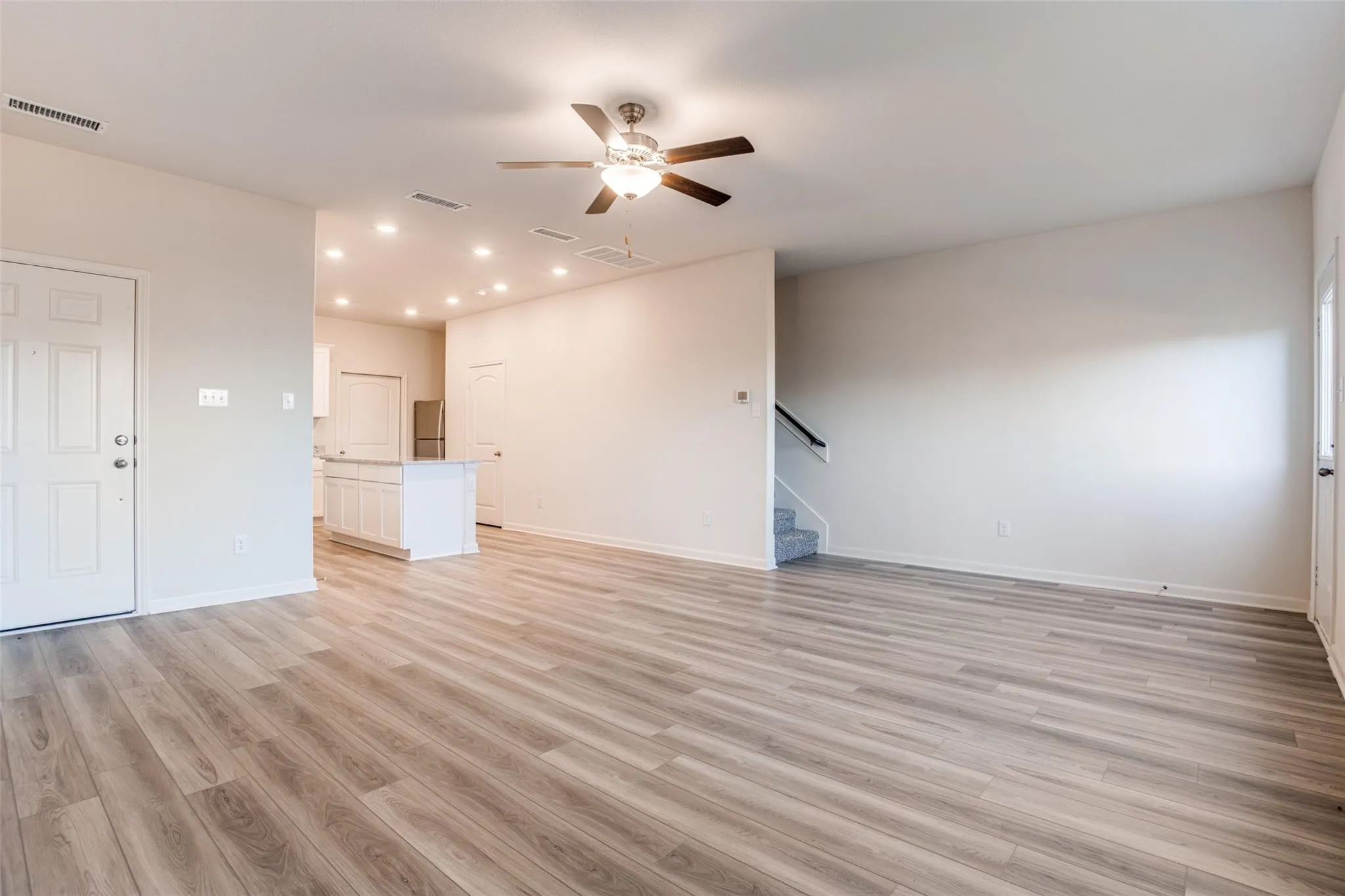 Open-concept living space with wood-finish flooring, recessed lighting, and a ceiling fan
