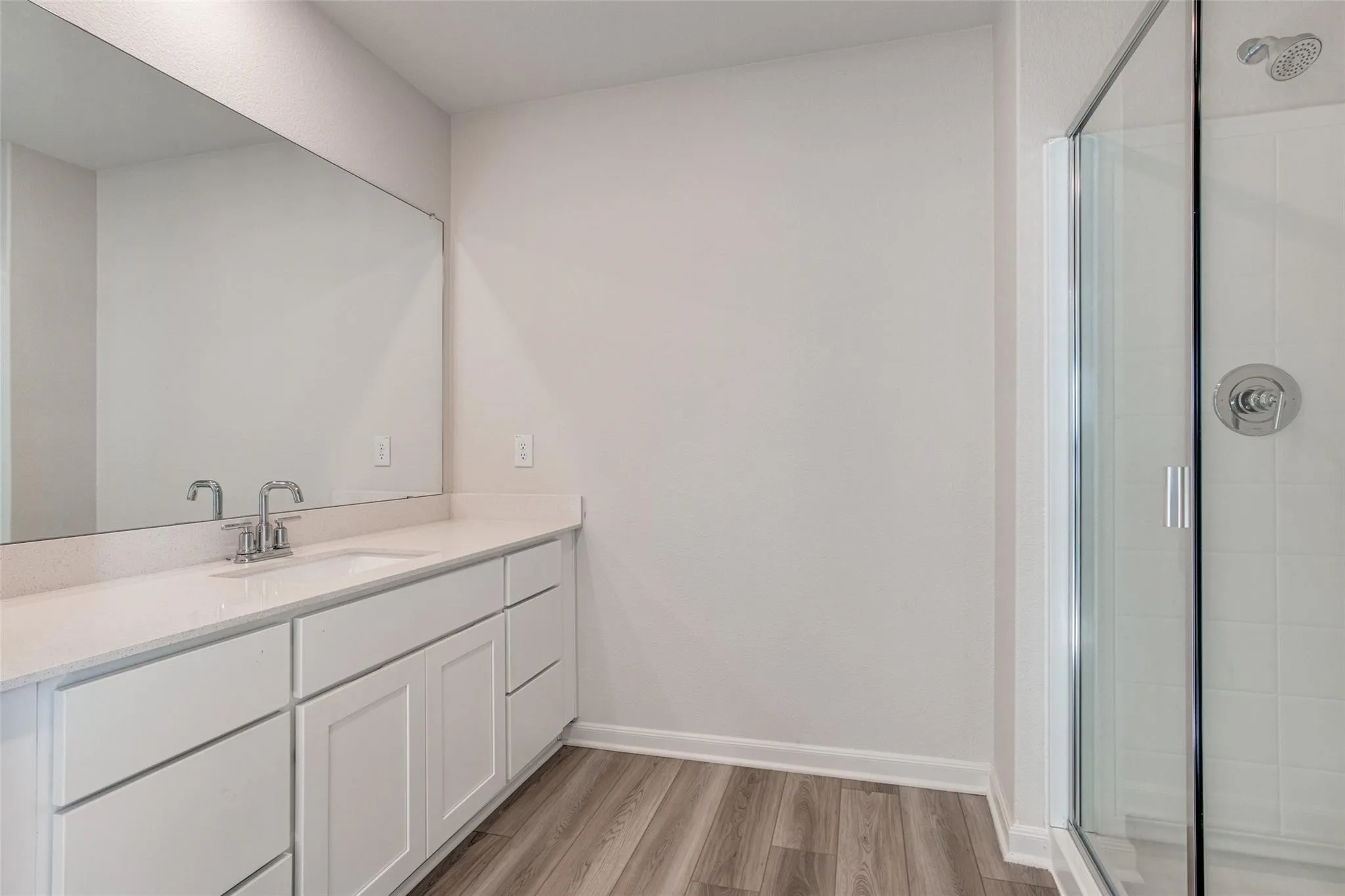 White vanity with a single basin, chrome faucet, and expansive wall mirror