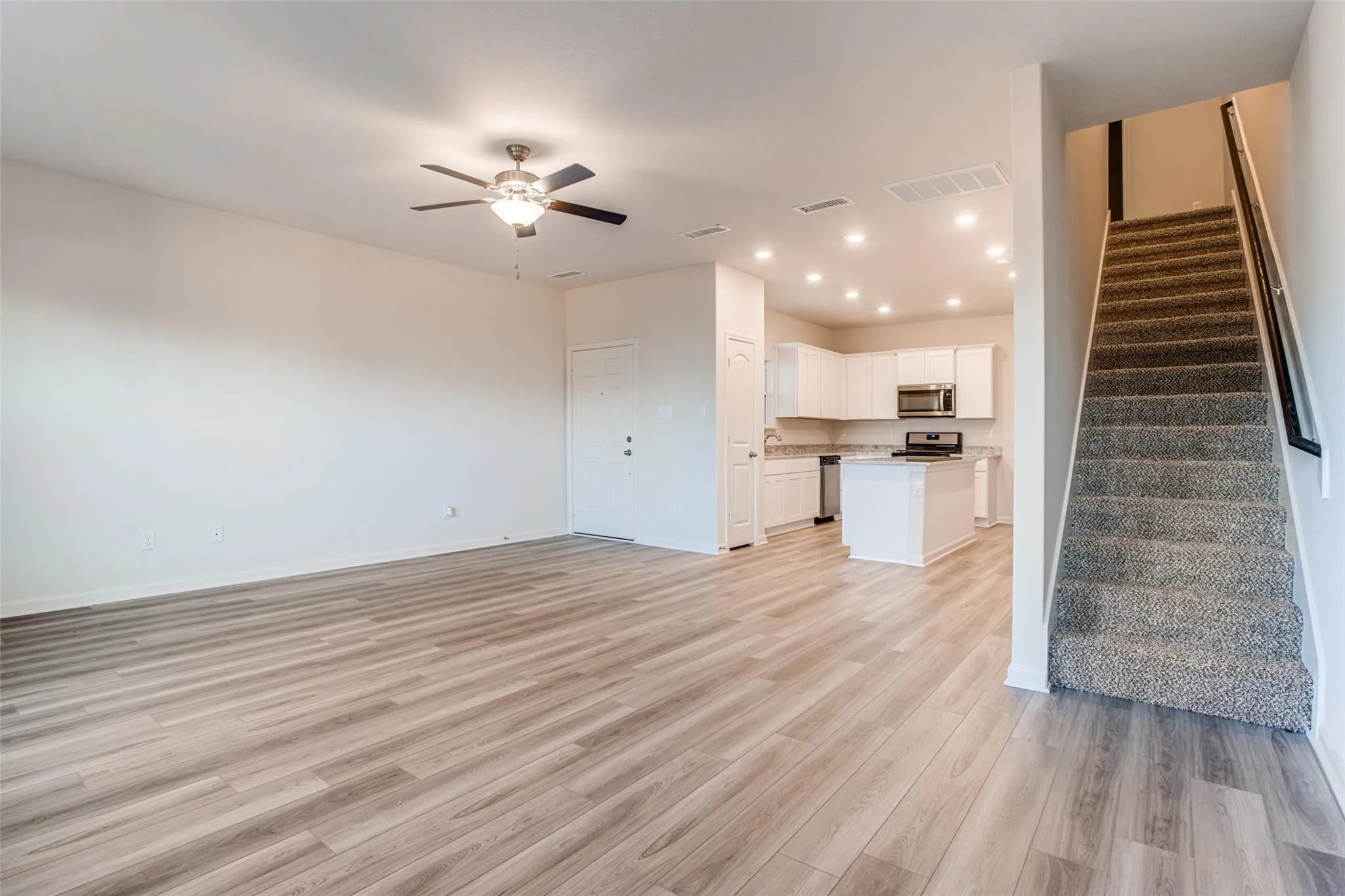 Open-concept living area with wood-finish flooring, a ceiling fan, and recessed lighting