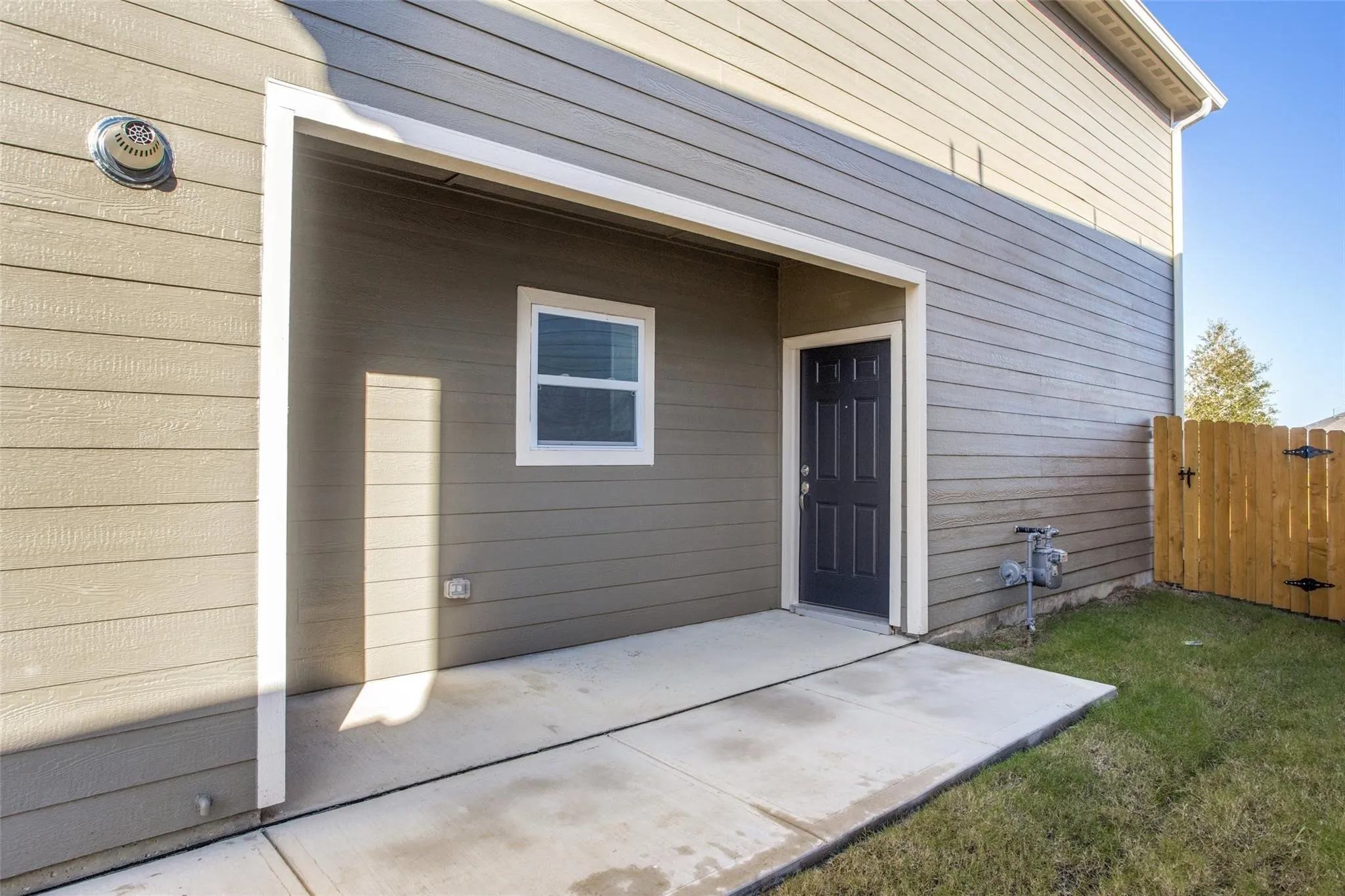 Concrete patio with a dark paneled door and a white-framed window