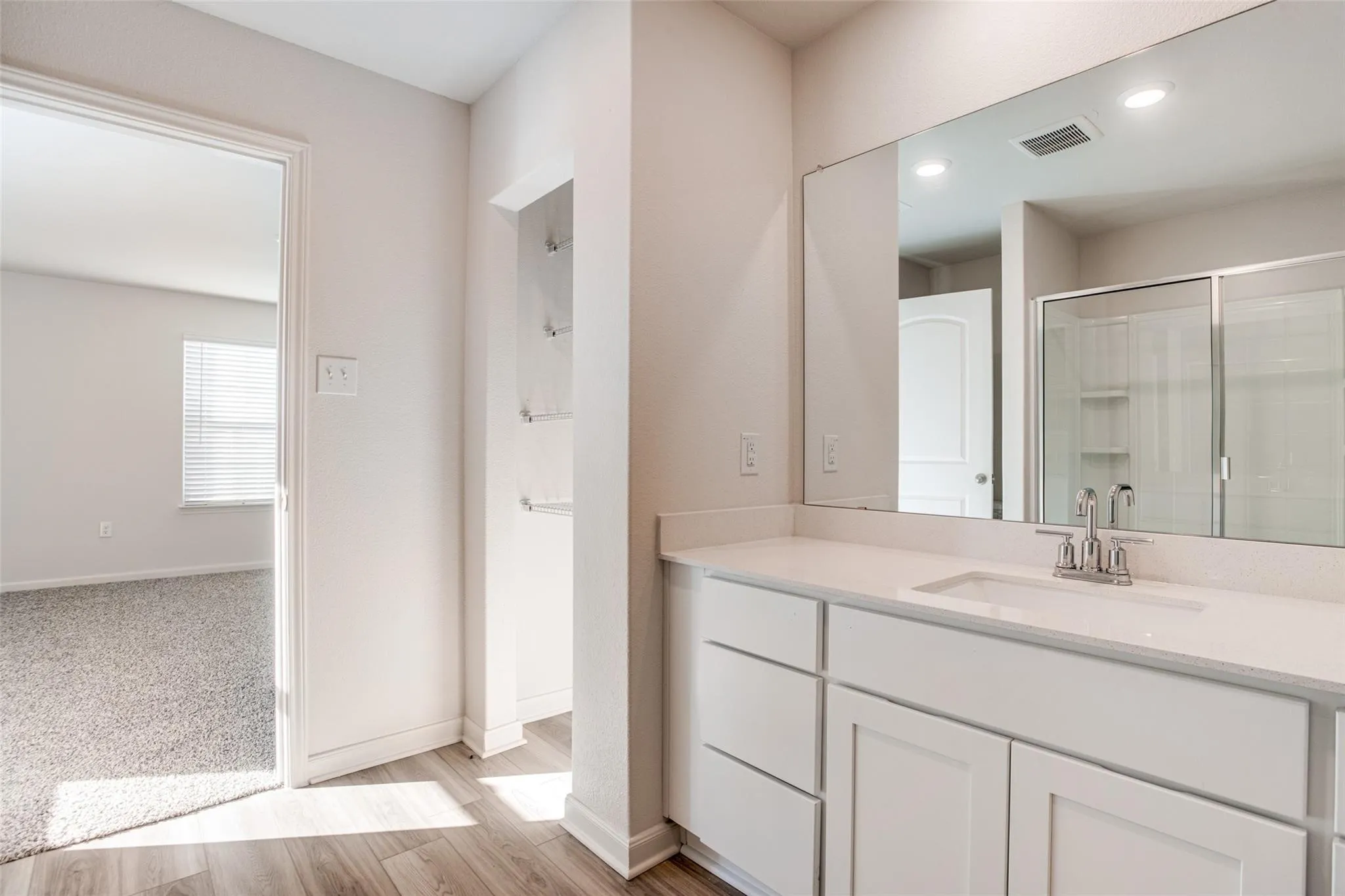 Bathroom vanity with a single basin, stainless steel faucet, and a large mirror