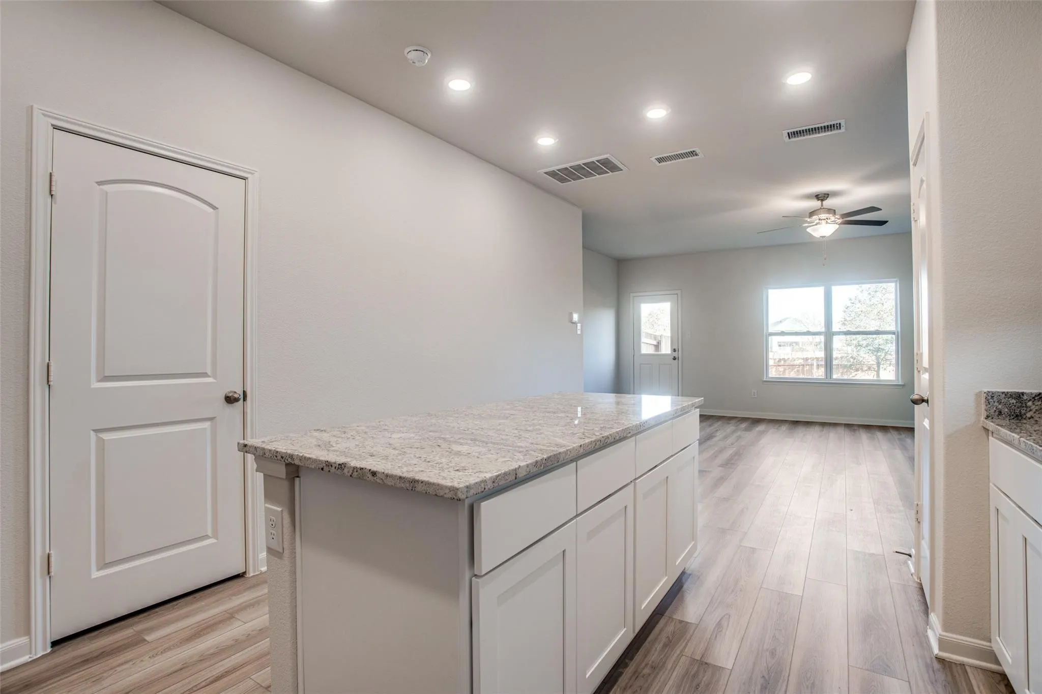Kitchen island with a light-toned countertop, white cabinetry, wood-finish flooring, recessed lighting, and a ceiling fan