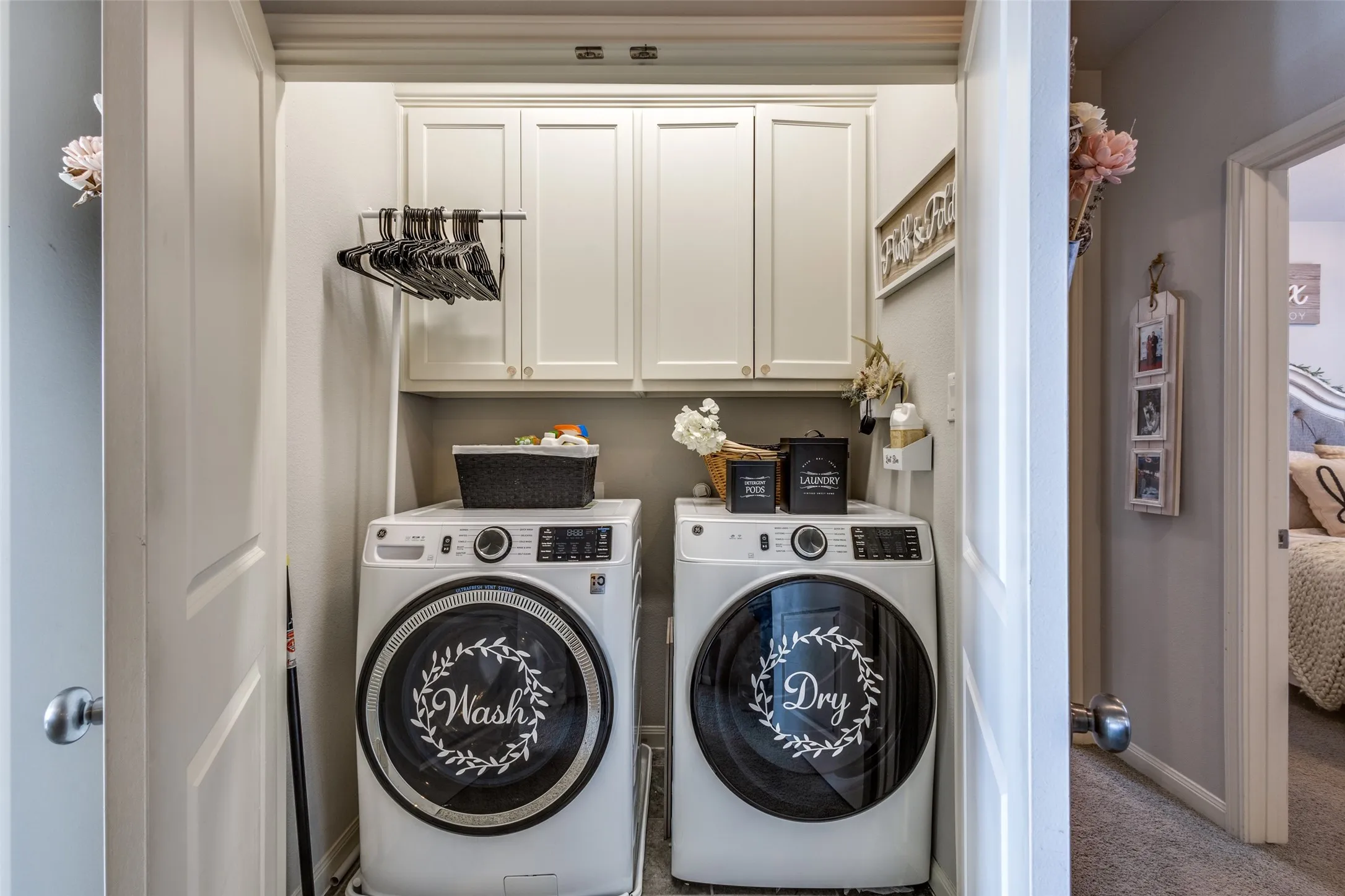Utility closet with overhead cabinetry, a built-in hanging rod, and light gray wall paint