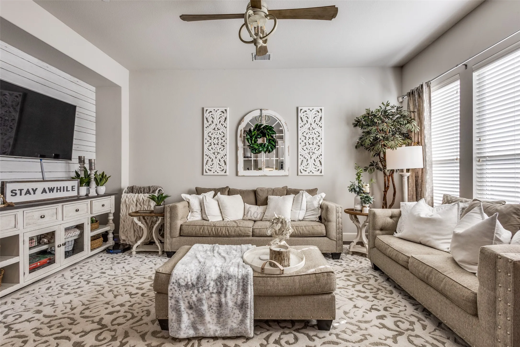 Recessed lighting, ceiling fan with wood-finish blades, and dual windows with blinds