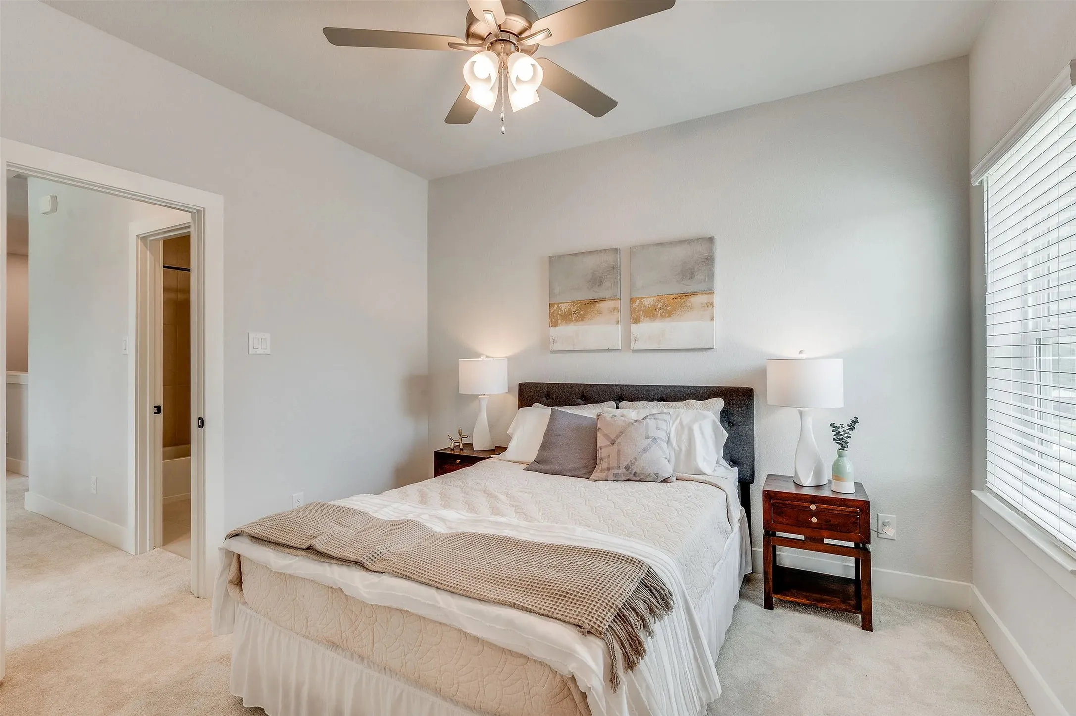Plush carpet flooring, a ceiling fan with integrated lighting, and a window with horizontal blinds