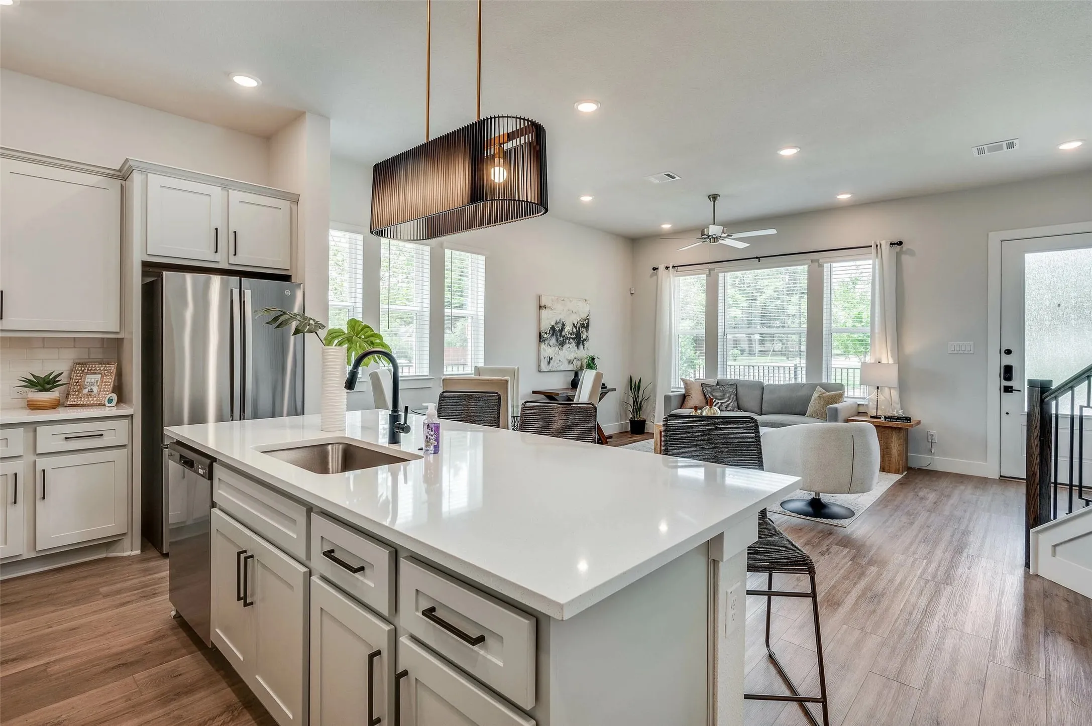 Expansive kitchen island with a single basin sink, light-colored countertops, and wood-finish flooring