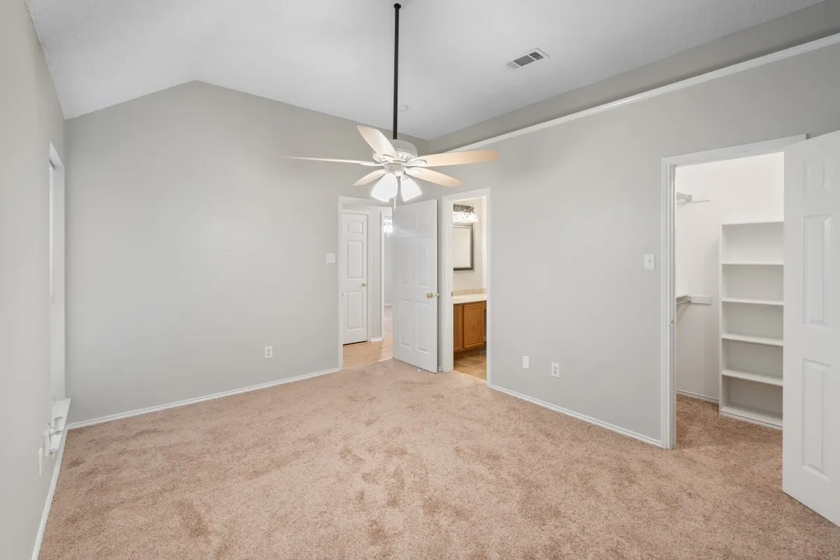 Primary bedroom with ceiling fan, full bathroom and walk in closet