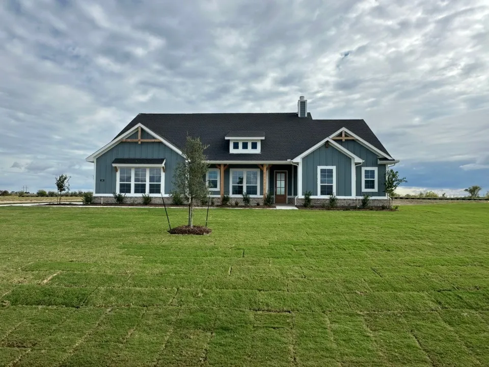 Craftsman-style exterior with board and batten siding, stone veneer foundation, dark shingle roof, and exposed wood beams