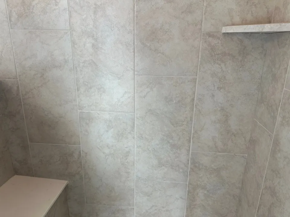 Tiled shower enclosure featuring a built-in corner shelf and a built-in bench