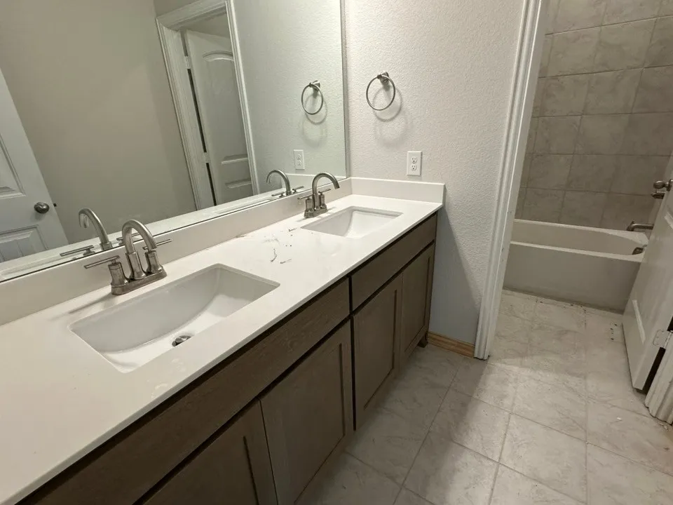 Dual vanity with integrated sinks, brushed nickel fixtures, under-counter storage, and a full-width mirror