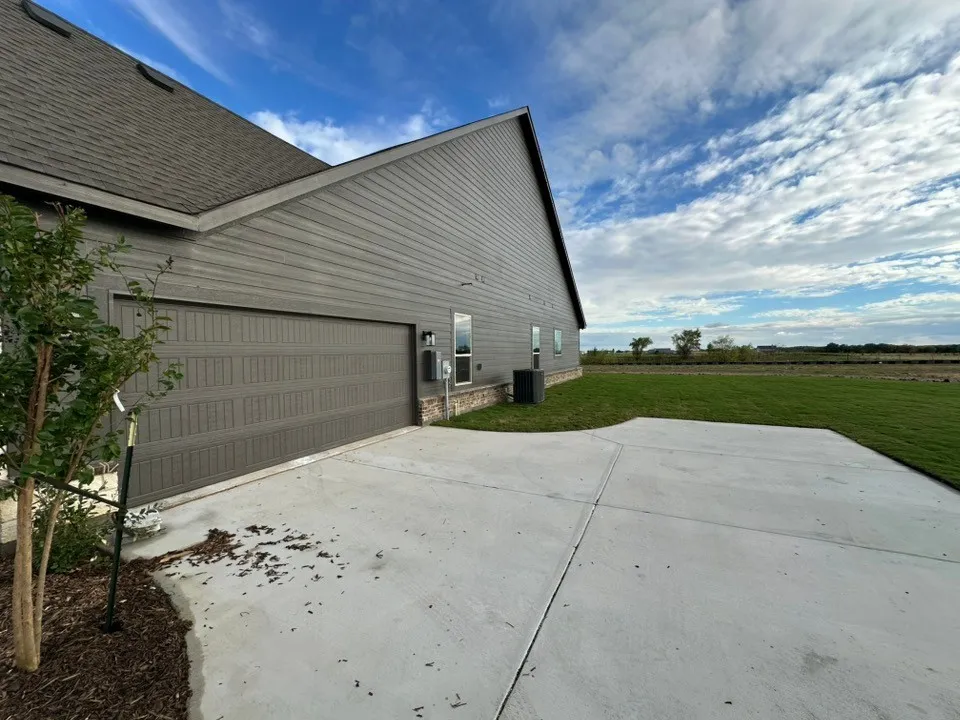 Attached garage with paneled door, gray siding, and window accents