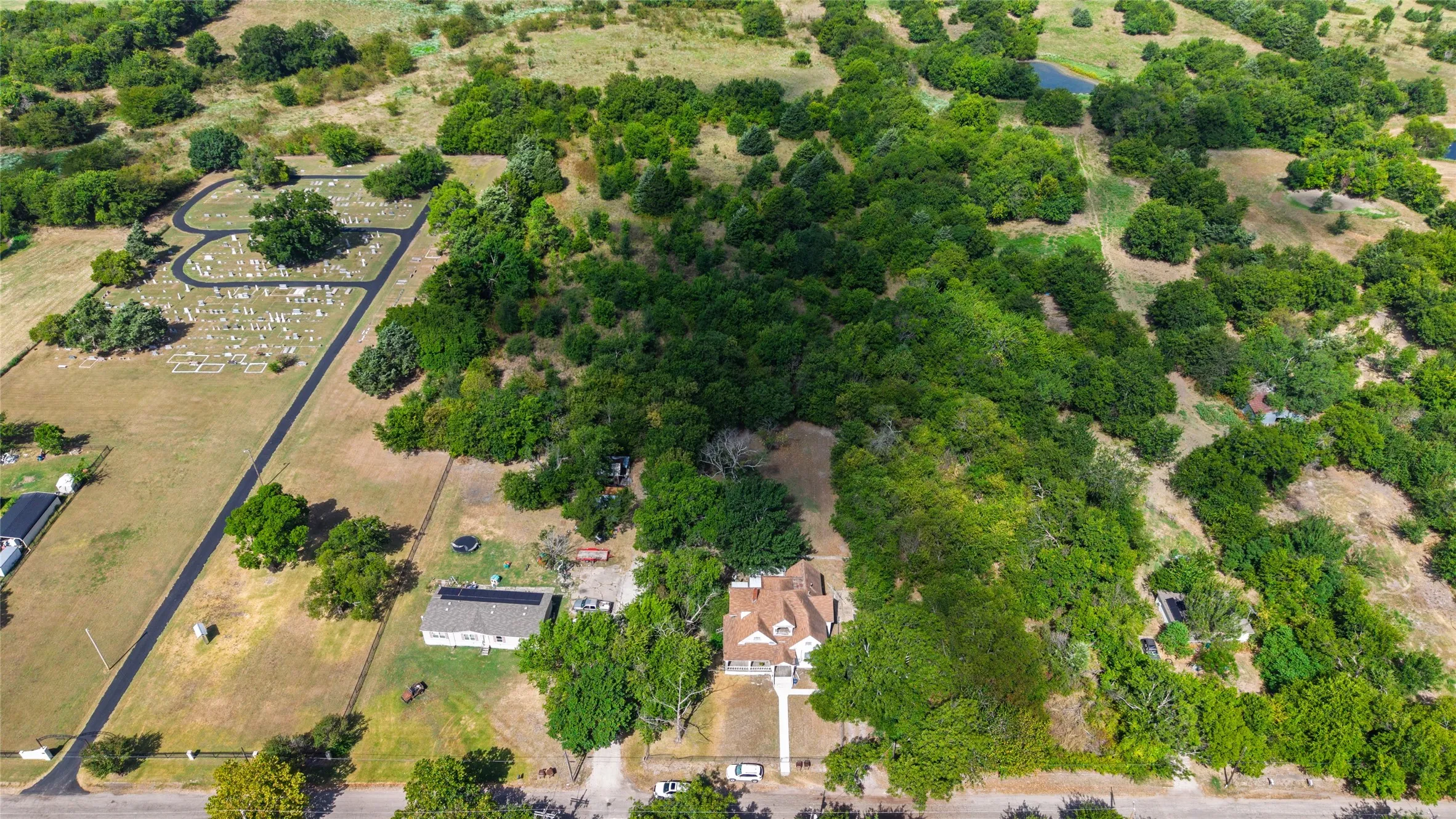 Expansive property featuring a main residence, an additional auxiliary structure, and substantial tree coverage