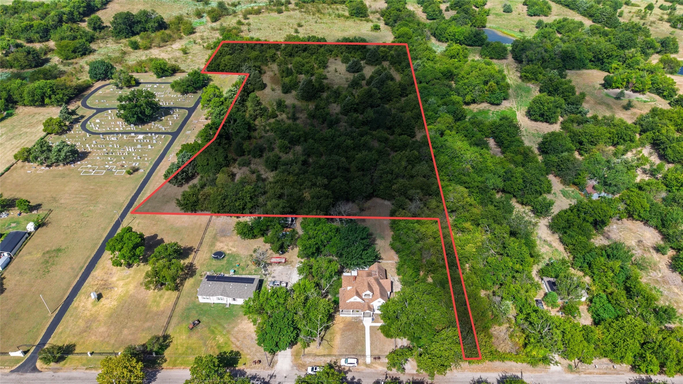 Expansive property featuring a two-story residence, mature trees, and a substantial portion of undeveloped land