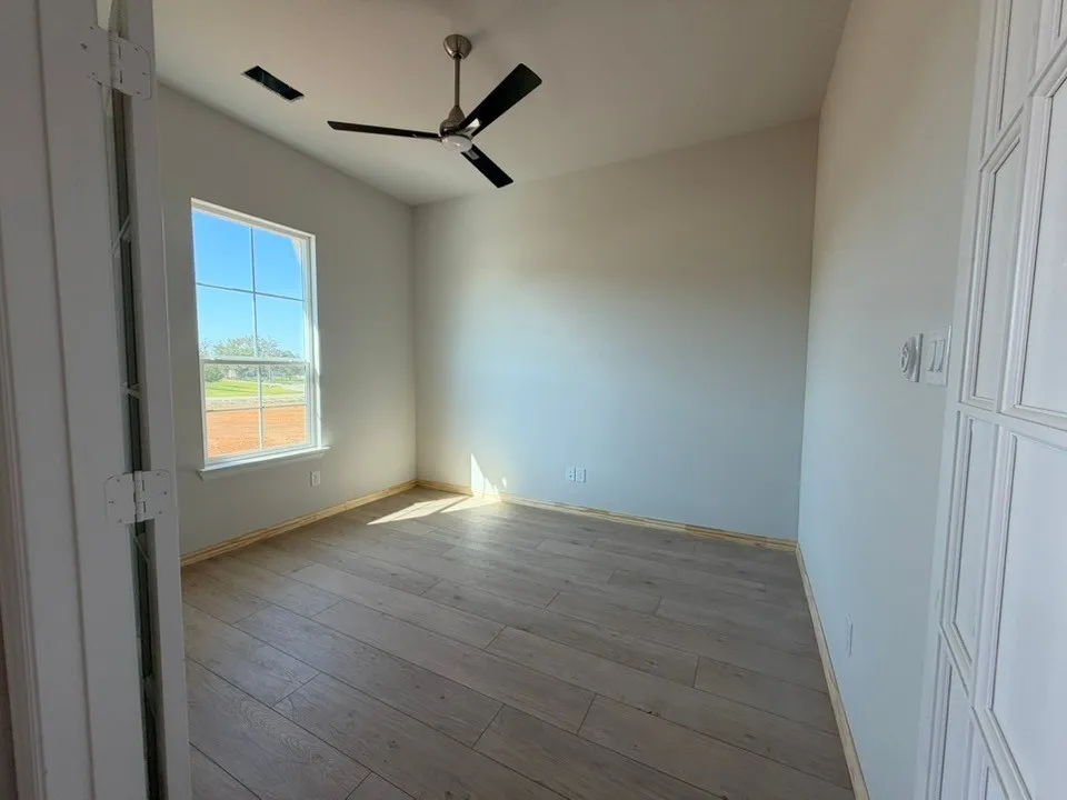 High ceilings, ceiling fan, wood-finish flooring, paneled door, and a multi-pane window