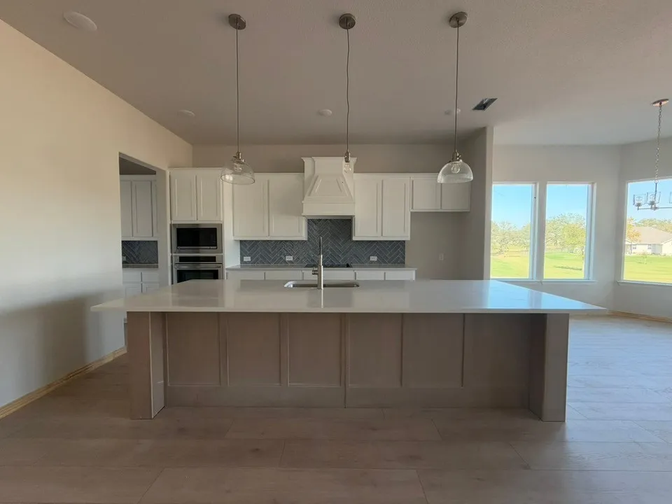 Kitchen island with a light-toned countertop, white cabinetry, and herringbone tile backsplash