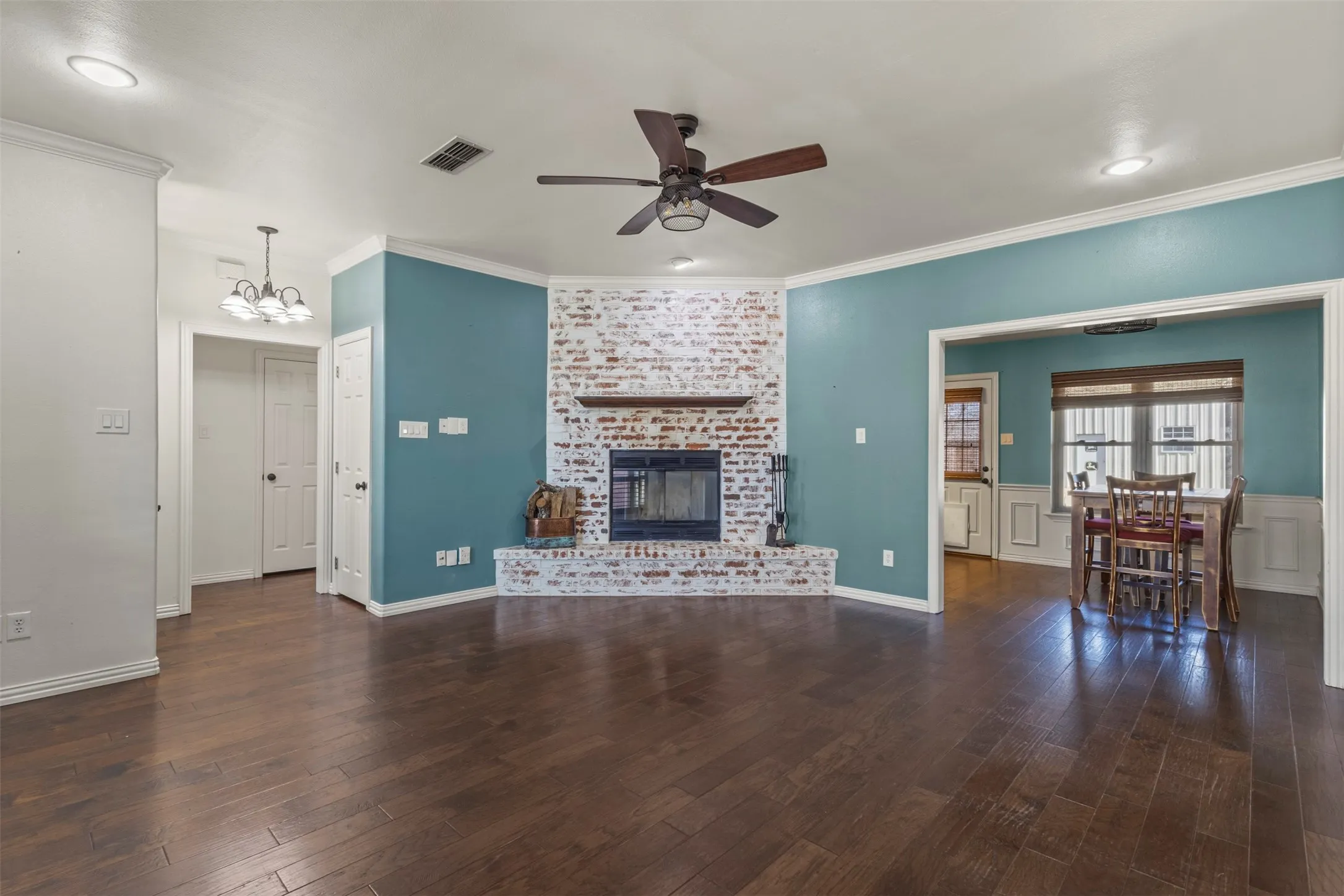 Hardwood flooring, corner brick fireplace with wood mantle, recessed lighting, ceiling fan, and crown molding
