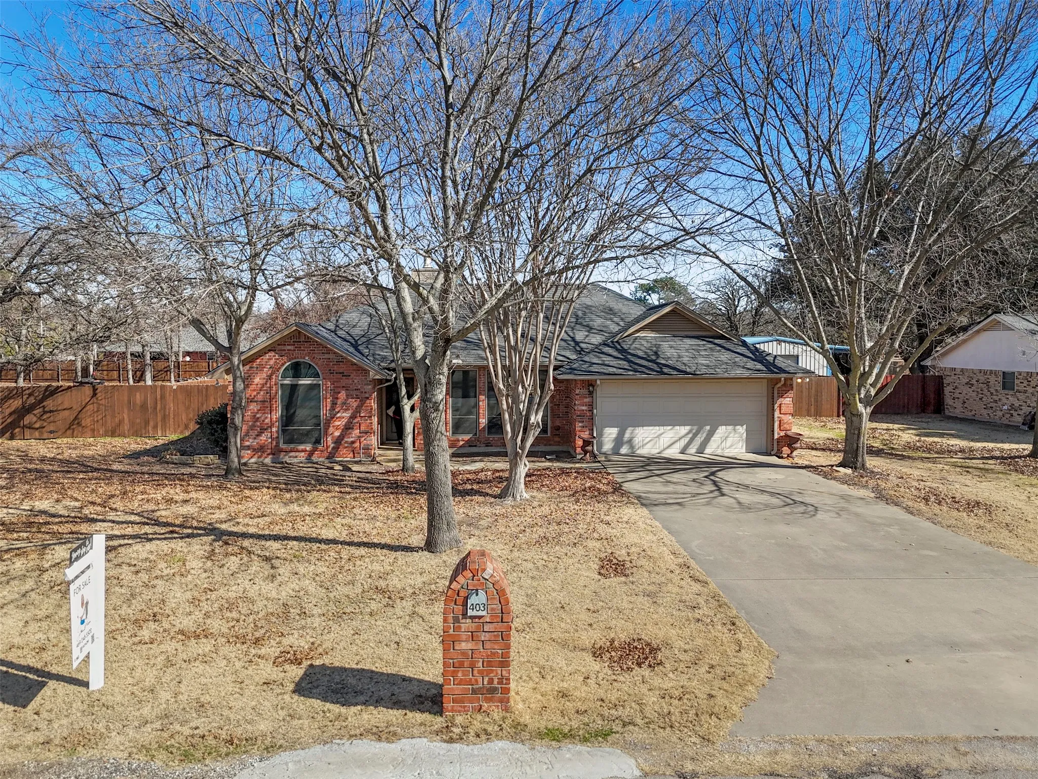 Brick exterior with an arched window, attached garage, and a concrete driveway