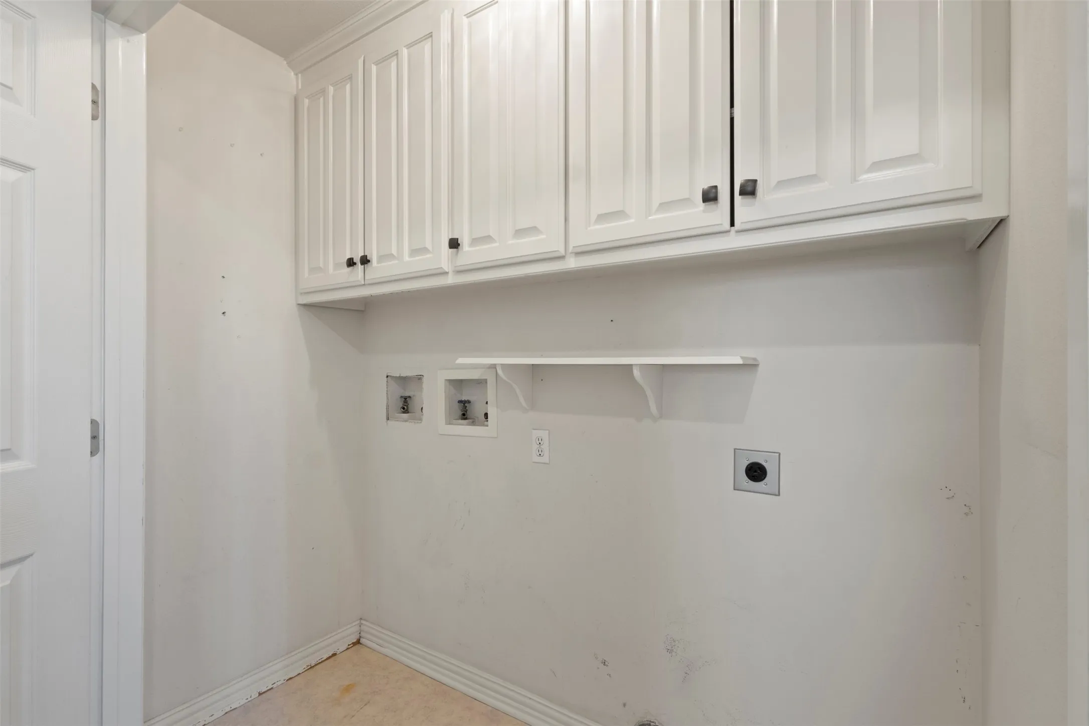 White shaker-style cabinetry with dark hardware, integrated shelving, and appliance hookups