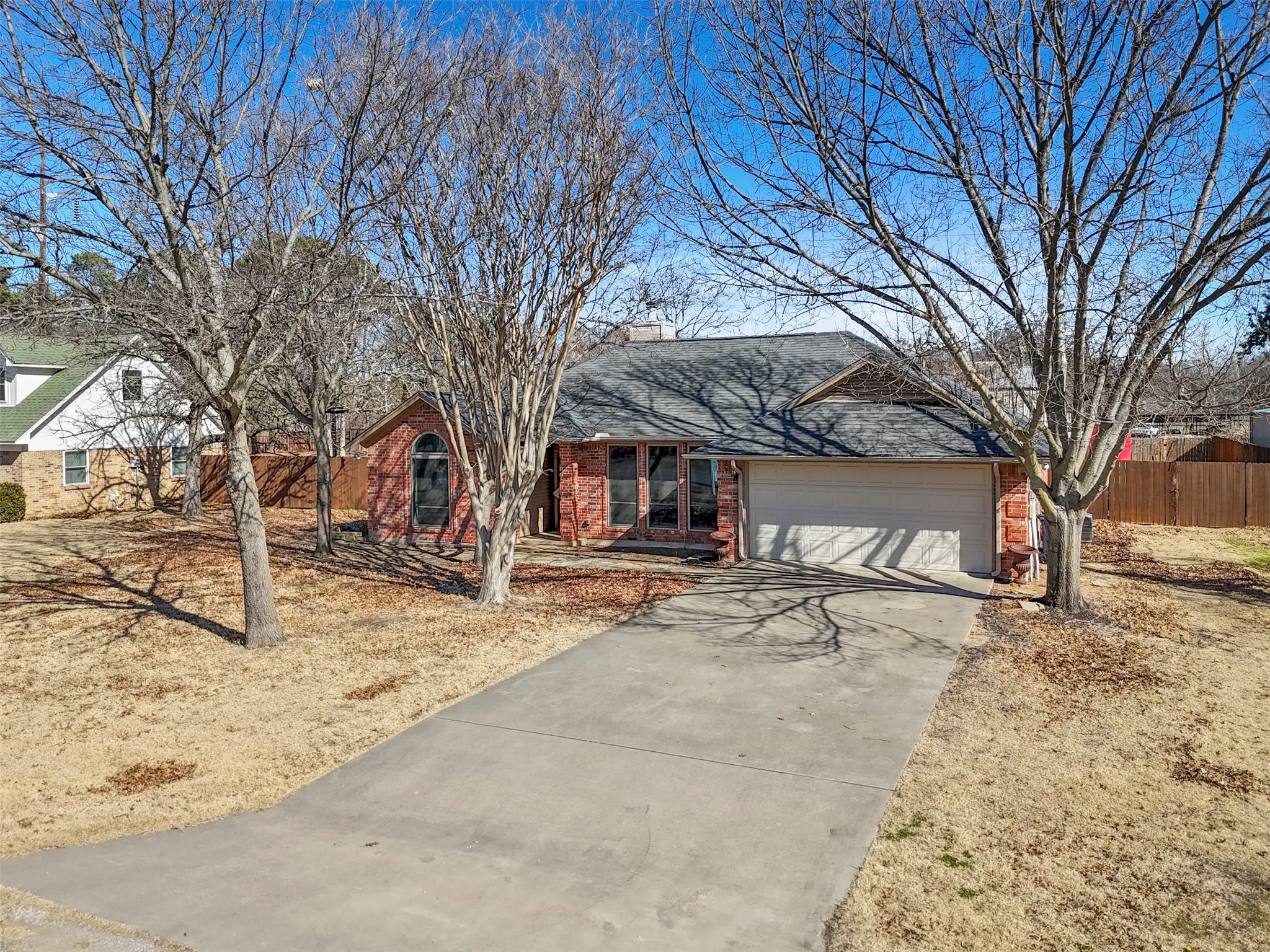 Traditional brick-clad home with an attached garage, a concrete driveway, and a front yard