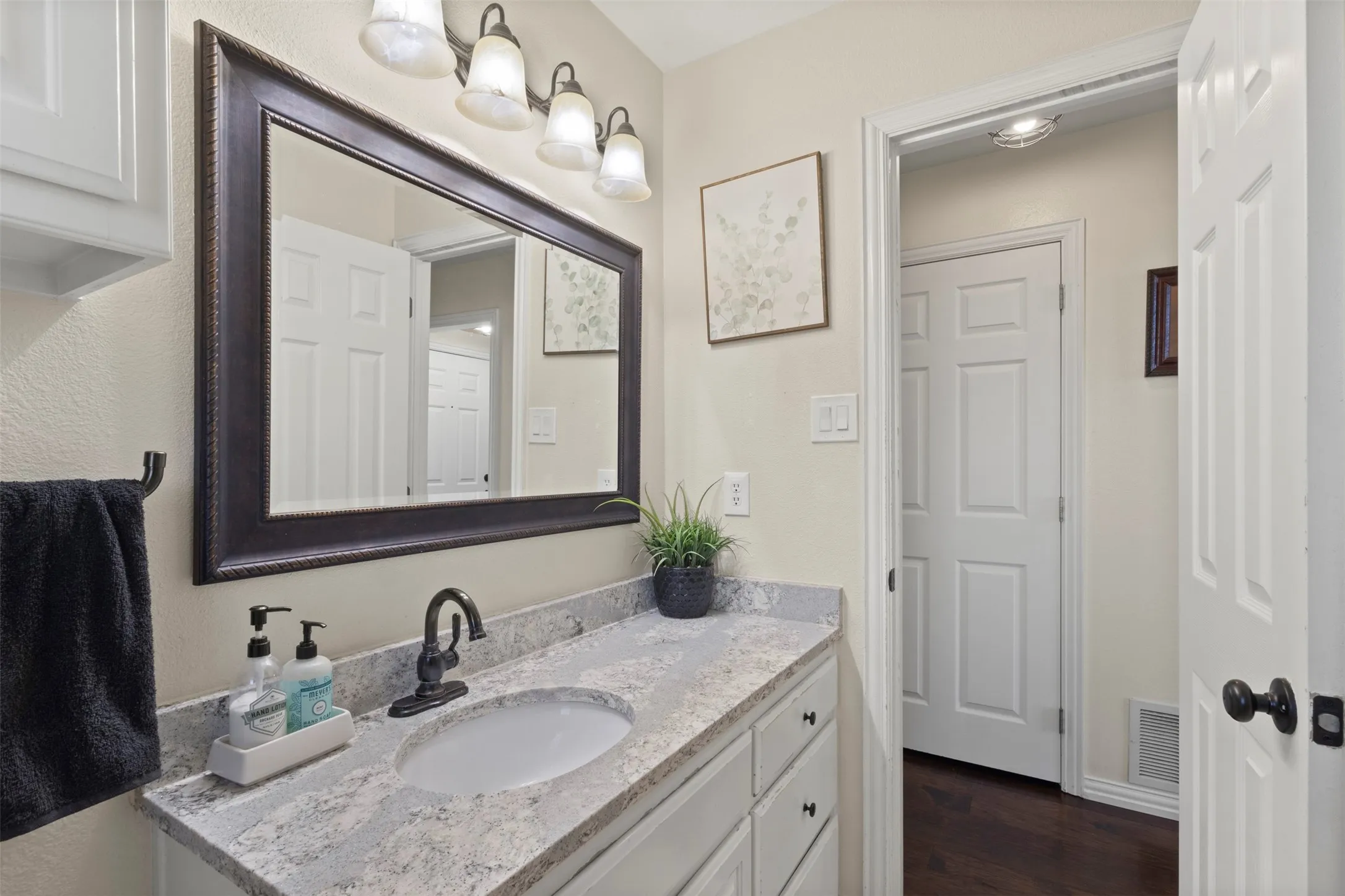 White vanity with black hardware, stone-finish countertop, and undermount sink