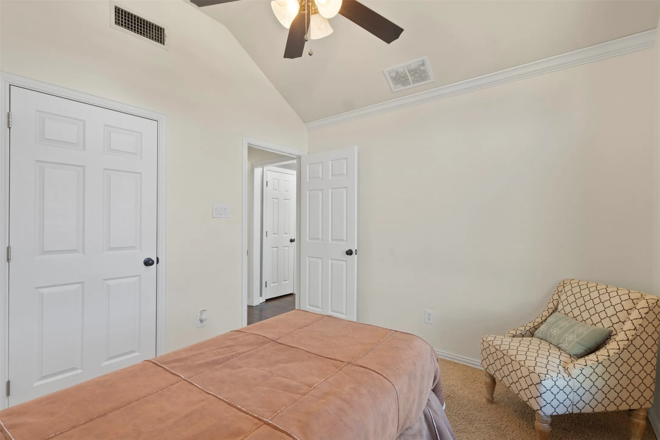 Vaulted ceiling with an attached ceiling fan, crown molding, and carpeted flooring