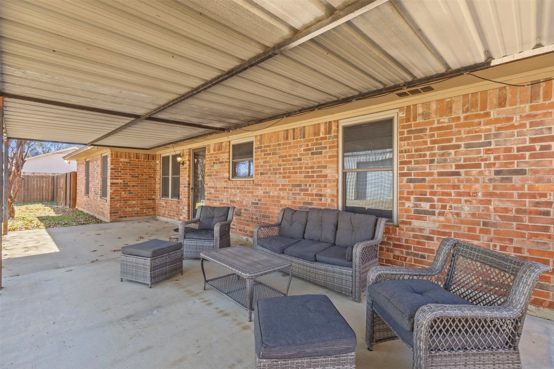 Covered patio with a concrete surface, brick exterior, and multiple windows