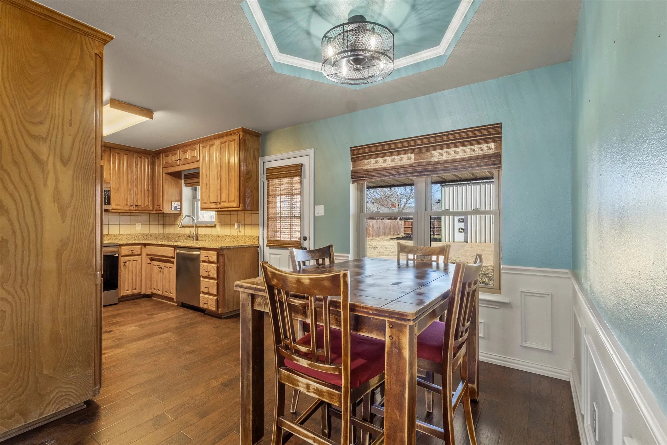 Kitchen with wood-finish flooring, wood cabinetry, stone countertops, and a tile backsplash
