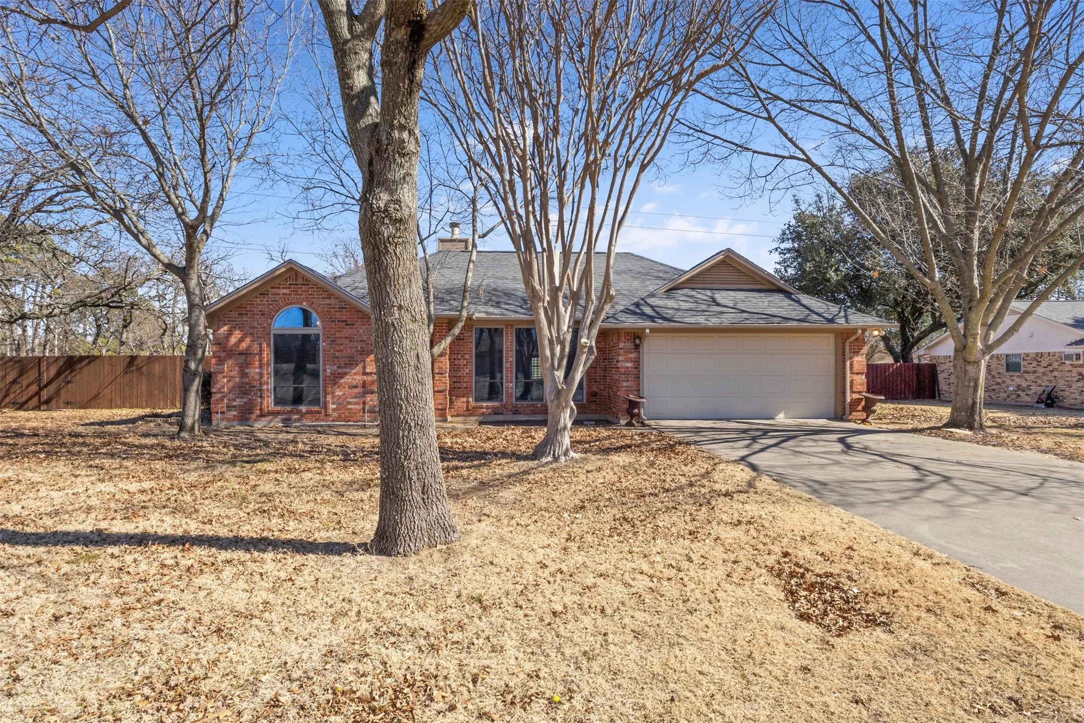 Brick exterior with arched window, attached garage, and pitched roof