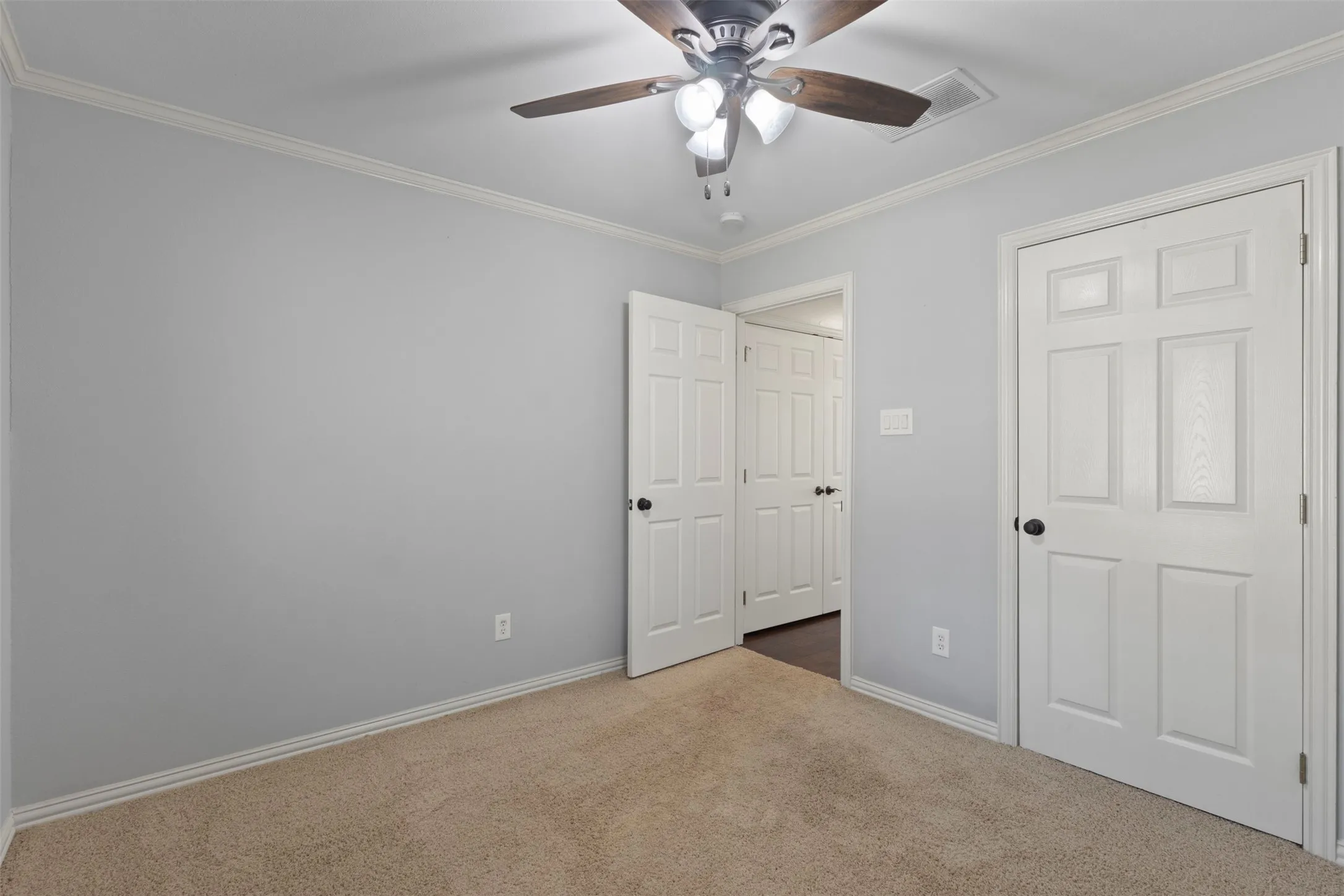 Neutral wall color, crown molding, ceiling fan with integrated lighting, carpeted flooring, and paneled interior doors