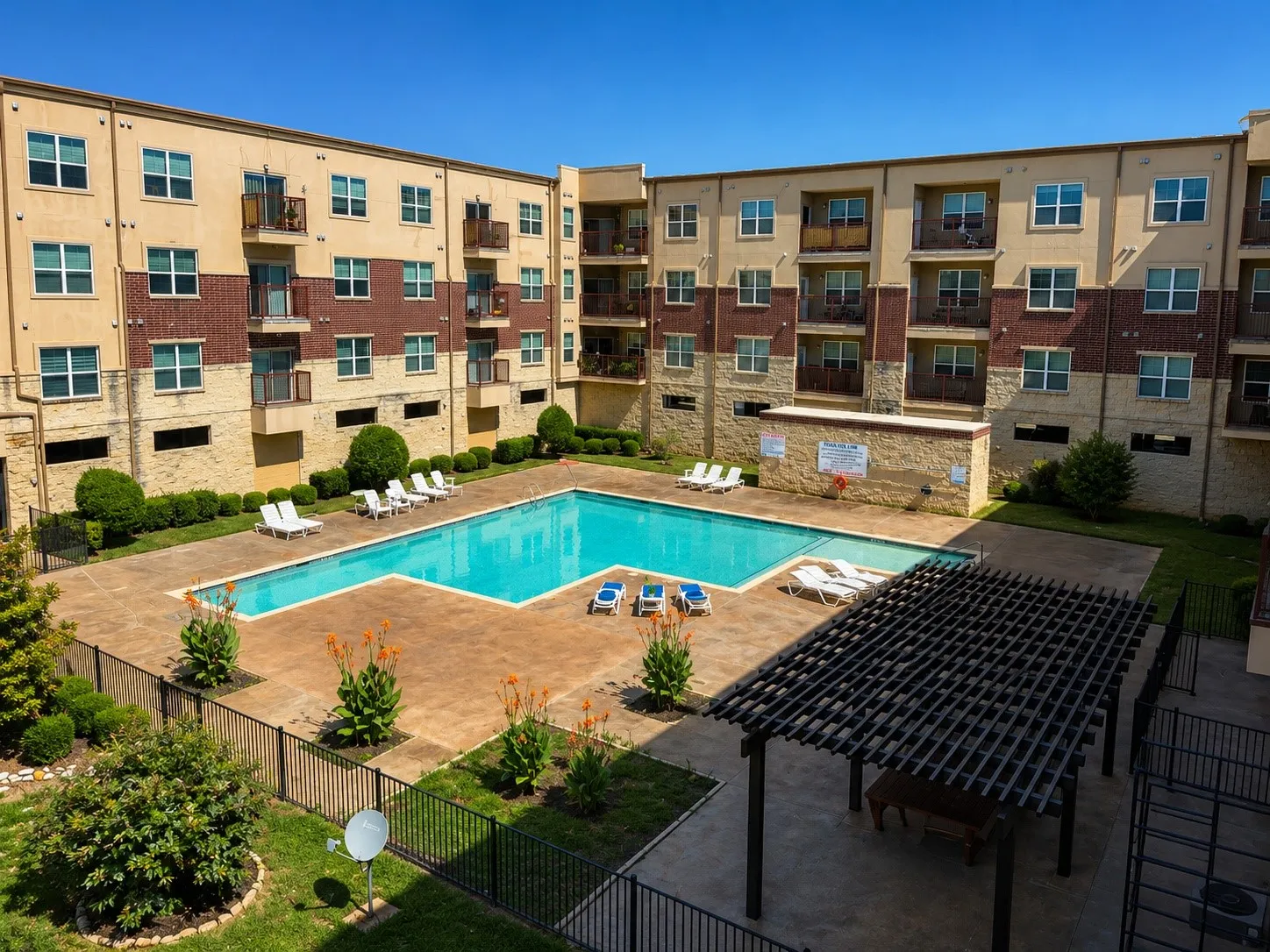 Outdoor swimming pool with an expansive paver deck, surrounded by a wrought-iron fence