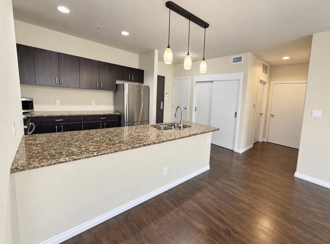 Kitchen featuring dark wood-finish cabinetry, stainless steel appliances, and a peninsula with granite-style countertops