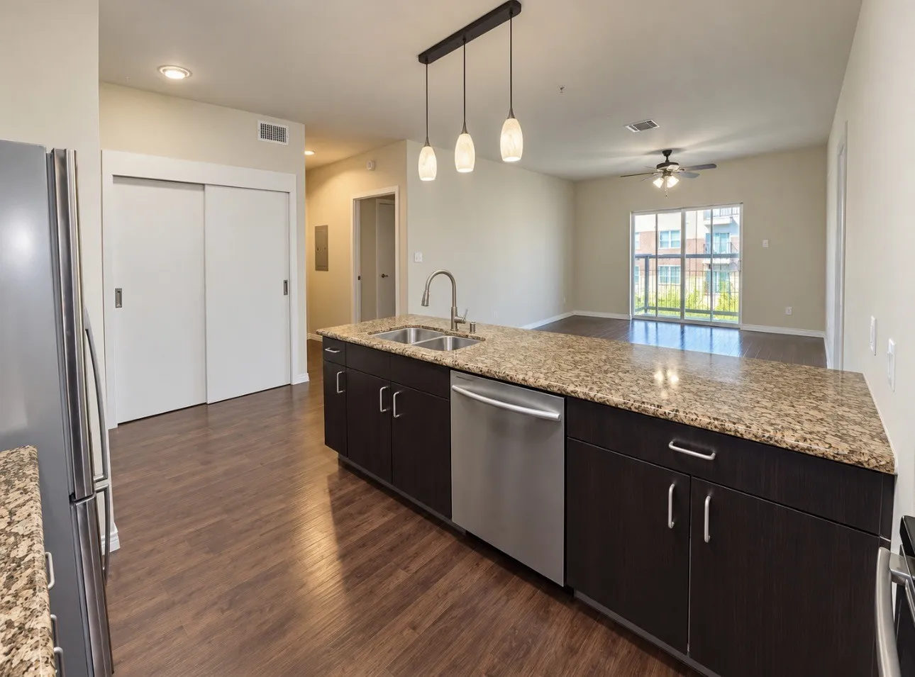 Kitchen island with granite-finish countertop, dual basin sink, and integrated dishwasher