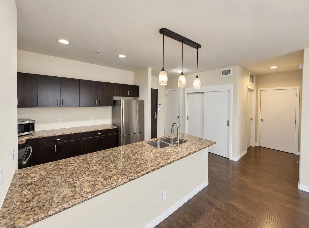Kitchen island featuring a dual basin sink and stone finish countertop