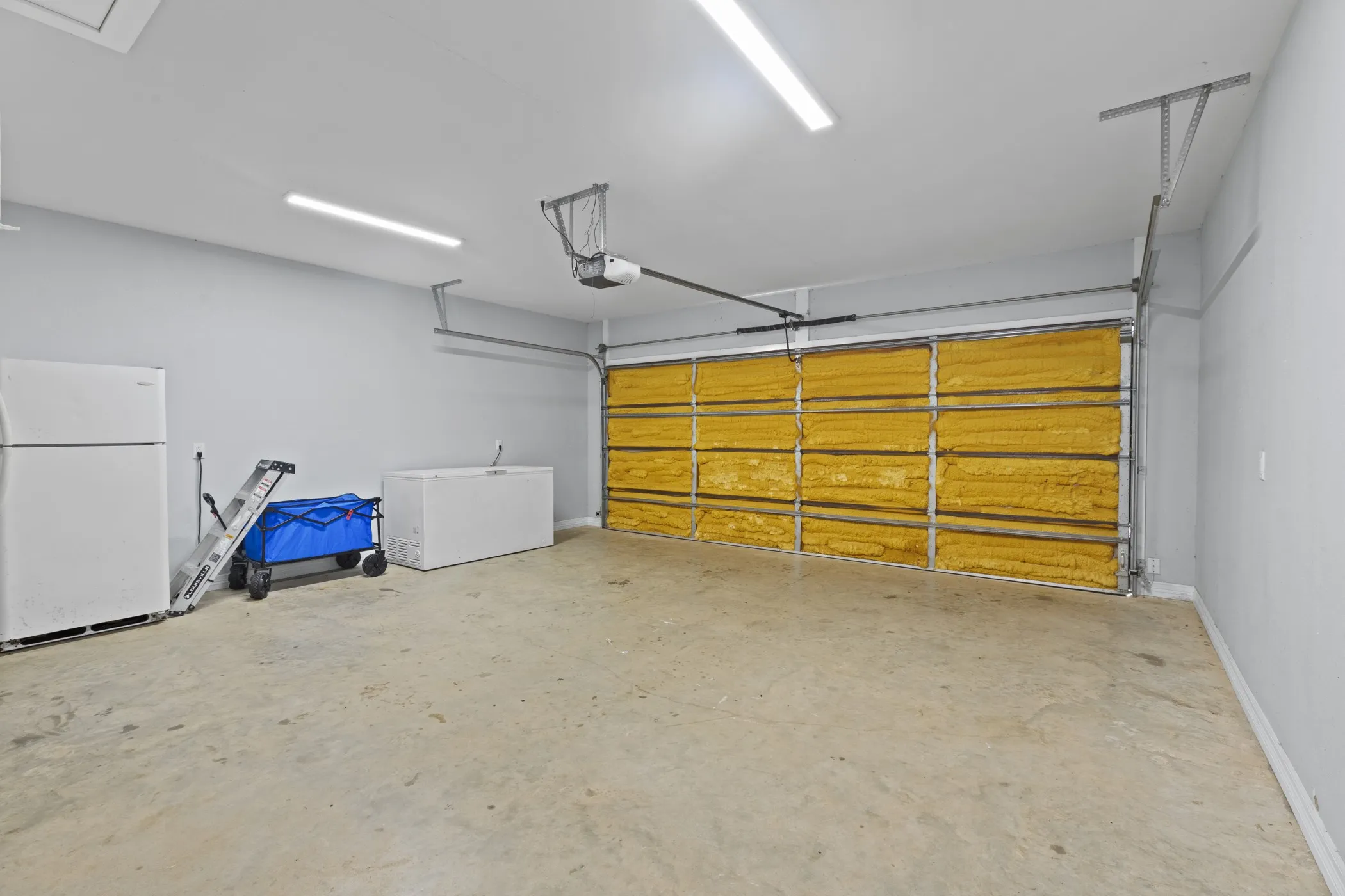Spacious garage with concrete flooring, light gray wall paint, and overhead lighting