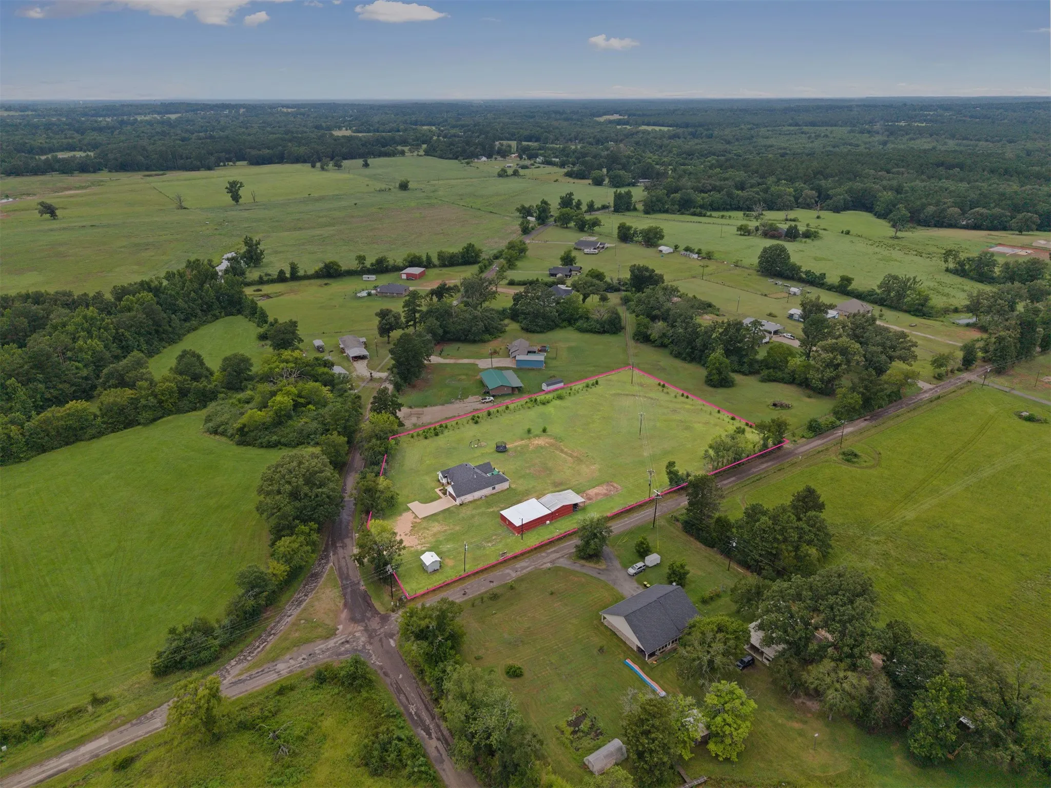 Expansive property featuring a residence, detached garage, and barn, surrounded by lush green fields