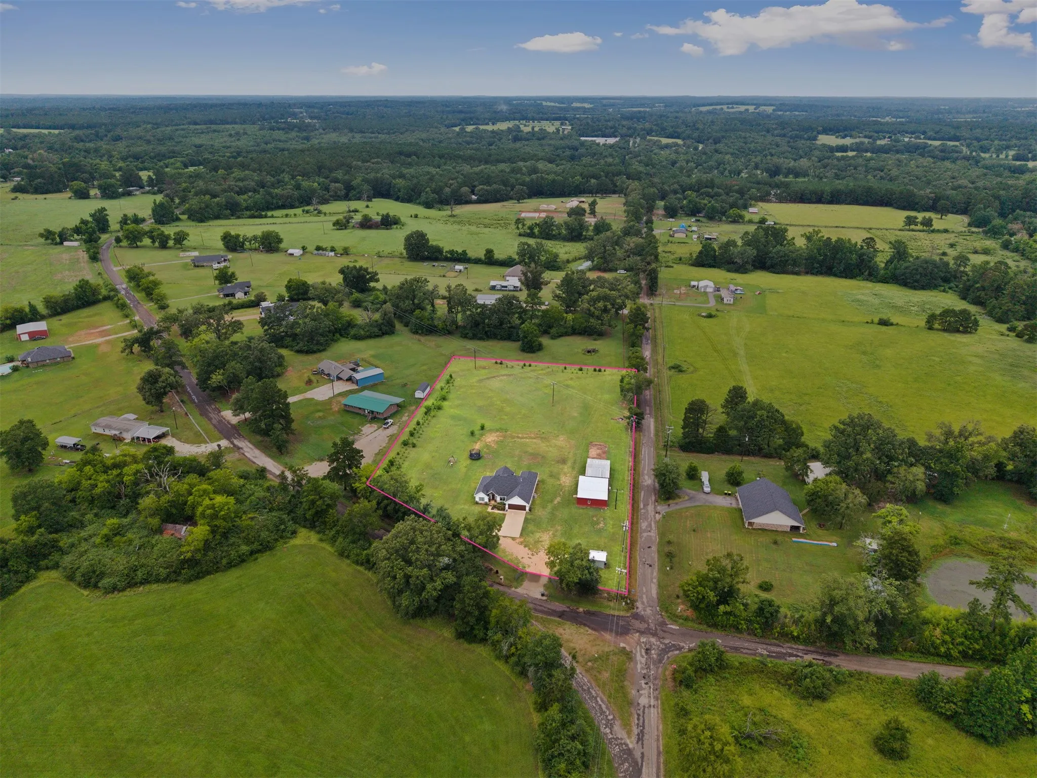 Expansive green landscape with scattered residential properties, mature trees, and a visible pond