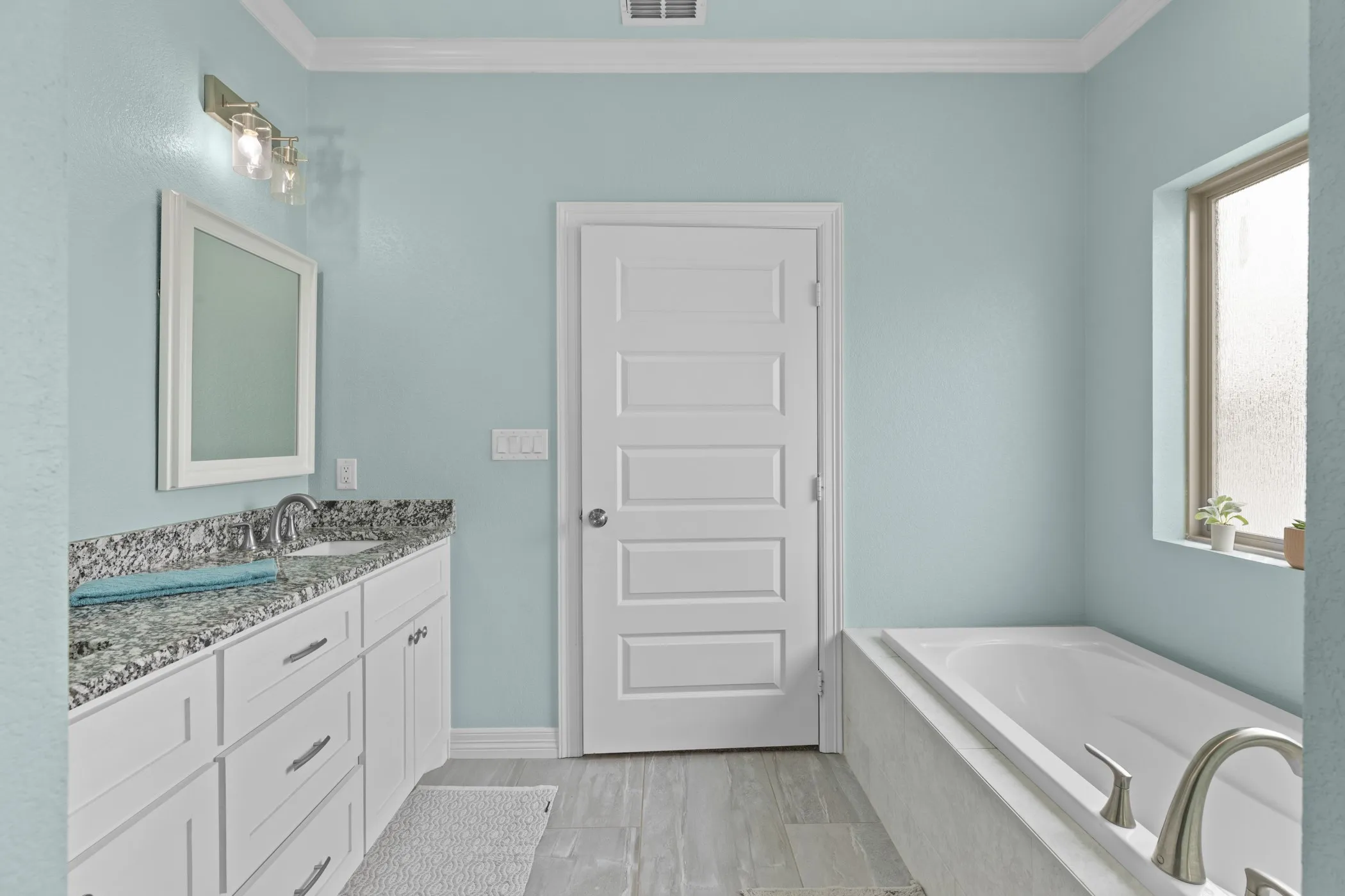 Bathroom featuring a single vanity with stone countertop, undermount sink, white cabinetry, and a built-in bathtub