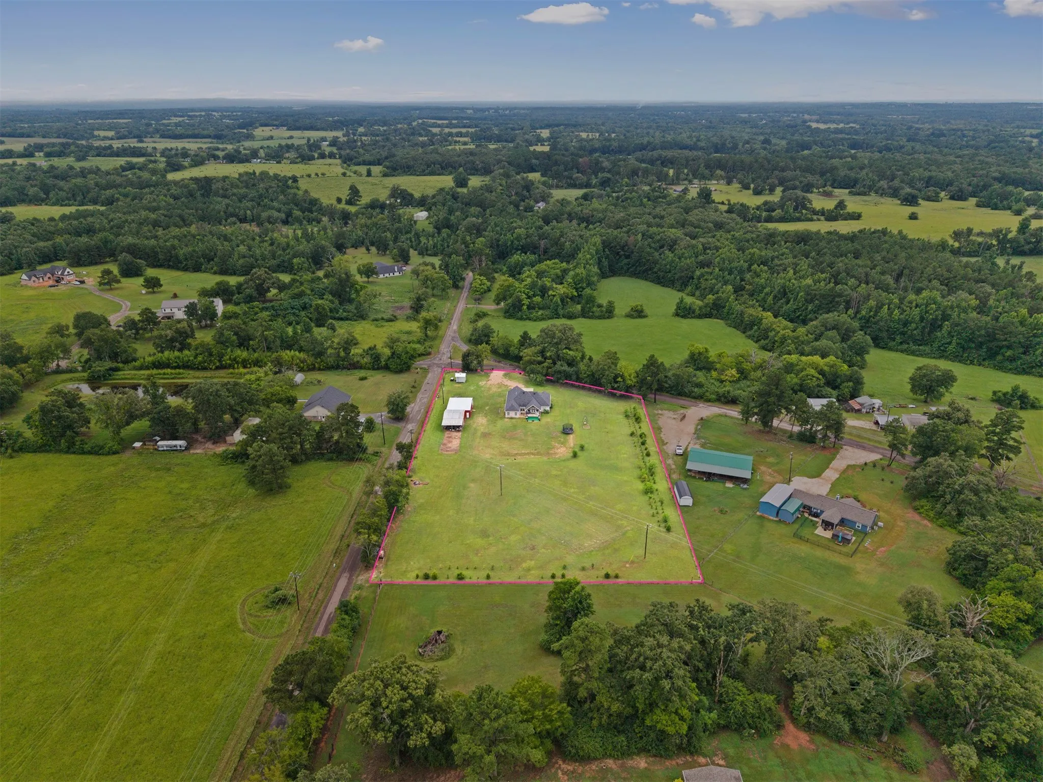 Expansive rural property featuring a main residence, multiple outbuildings, and mature trees