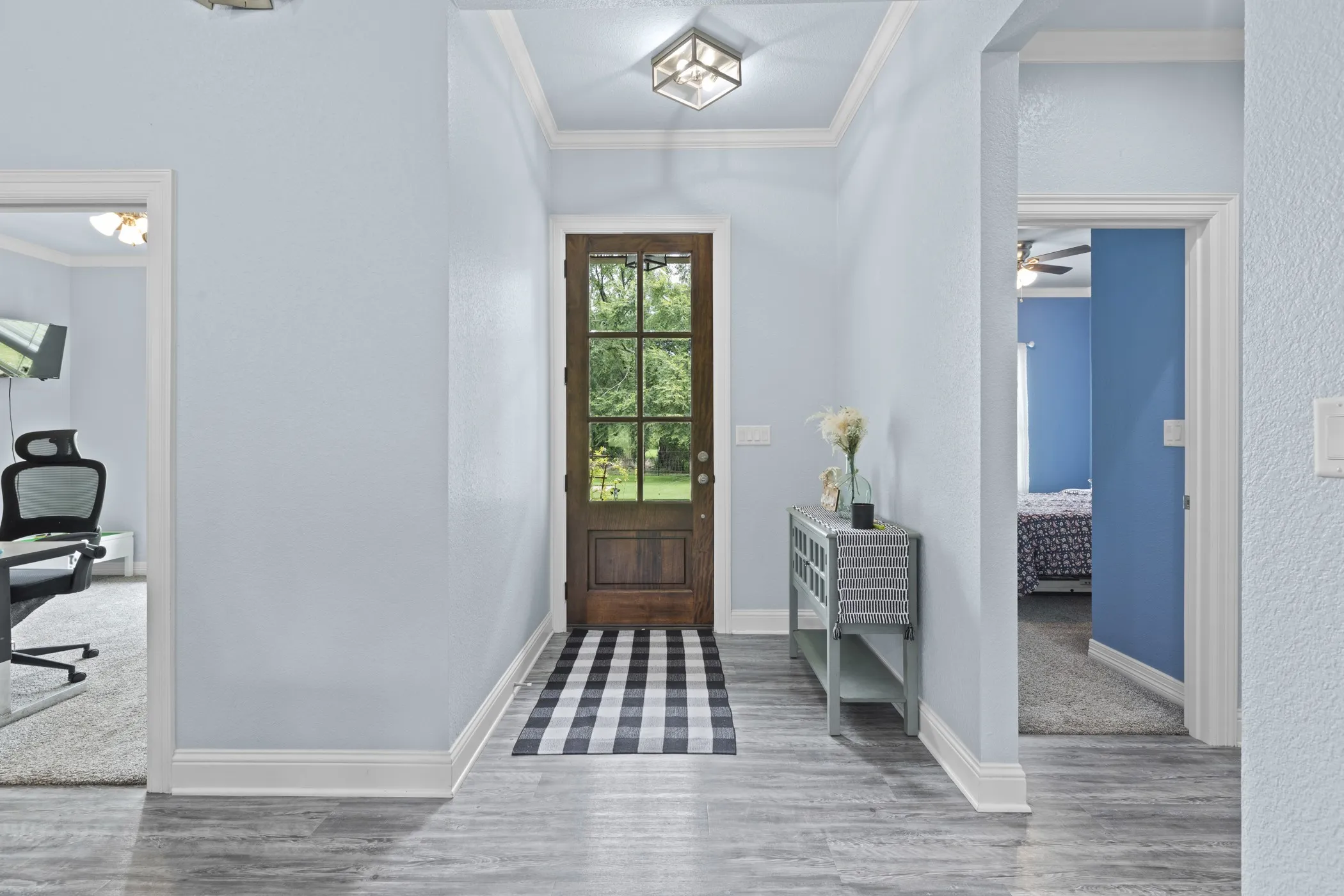 Wood-finish flooring throughout the entry, crown molding, and a solid wood front door with glass panels