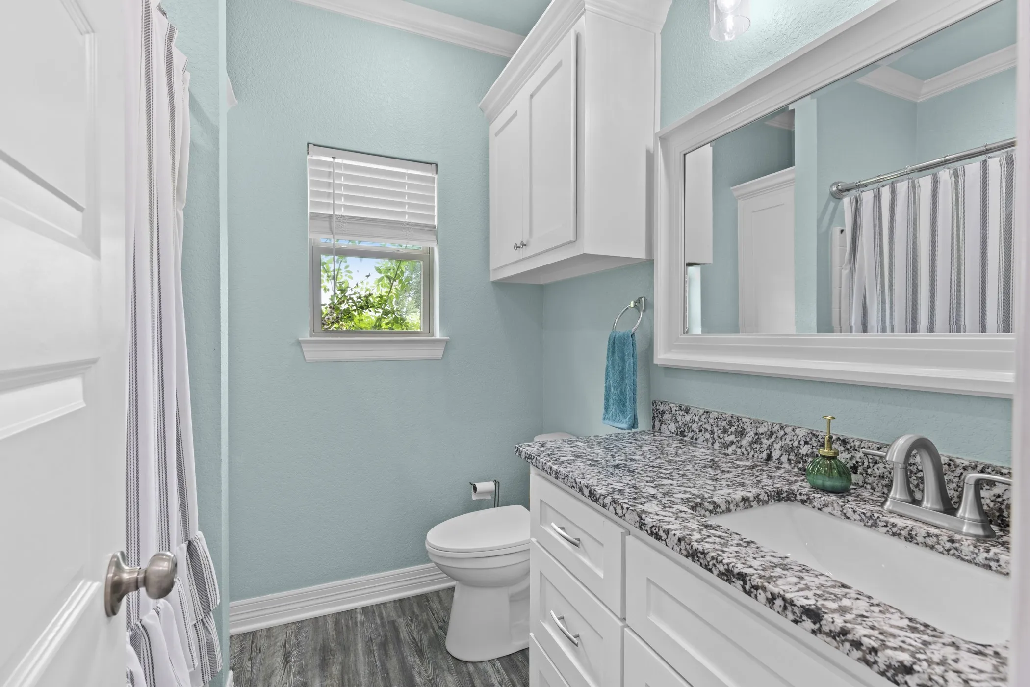 White shaker-style vanity with a granite countertop, undermount sink, and brushed nickel faucet