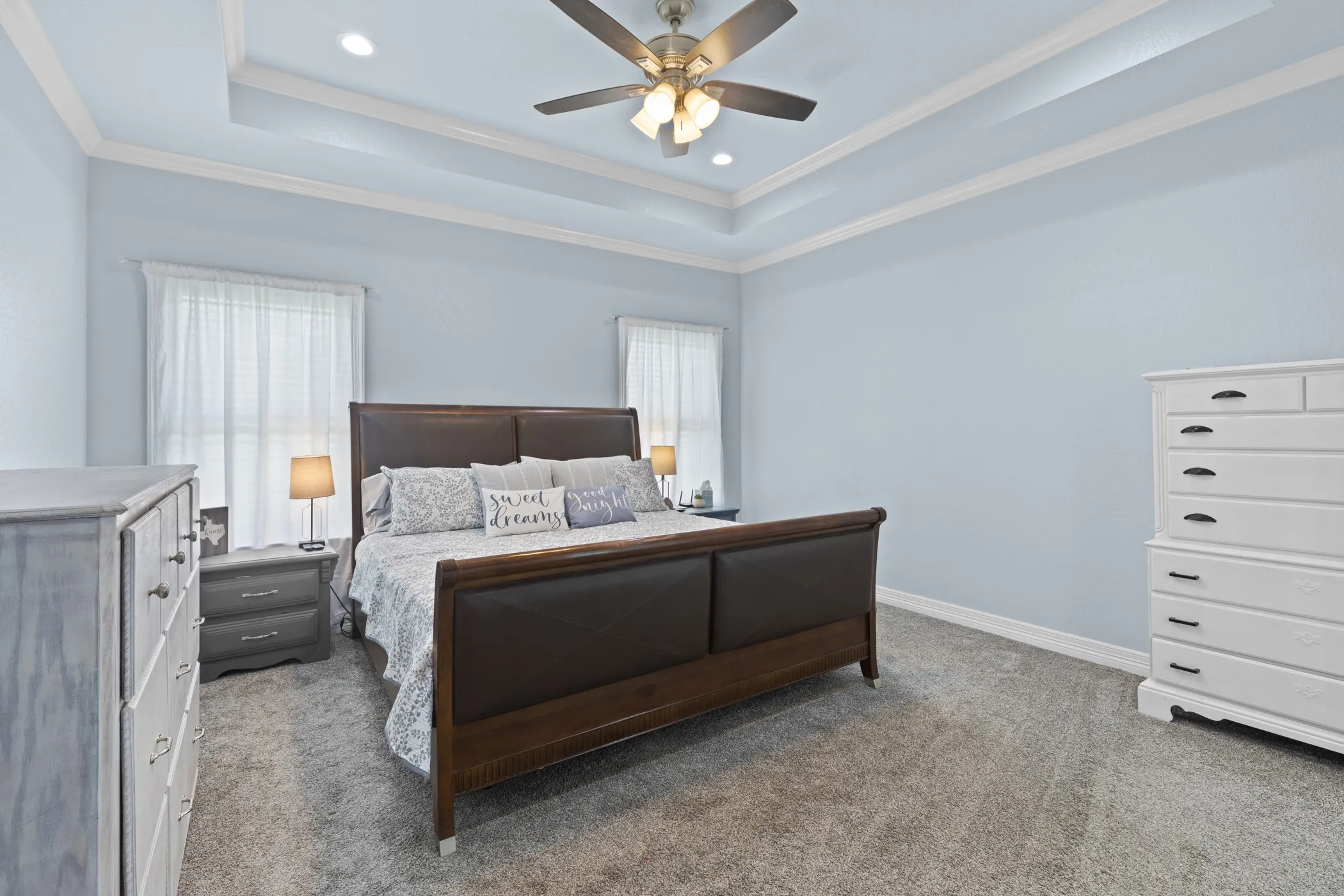 Tray ceiling with recessed lighting, ceiling fan, and light-toned wall finishes