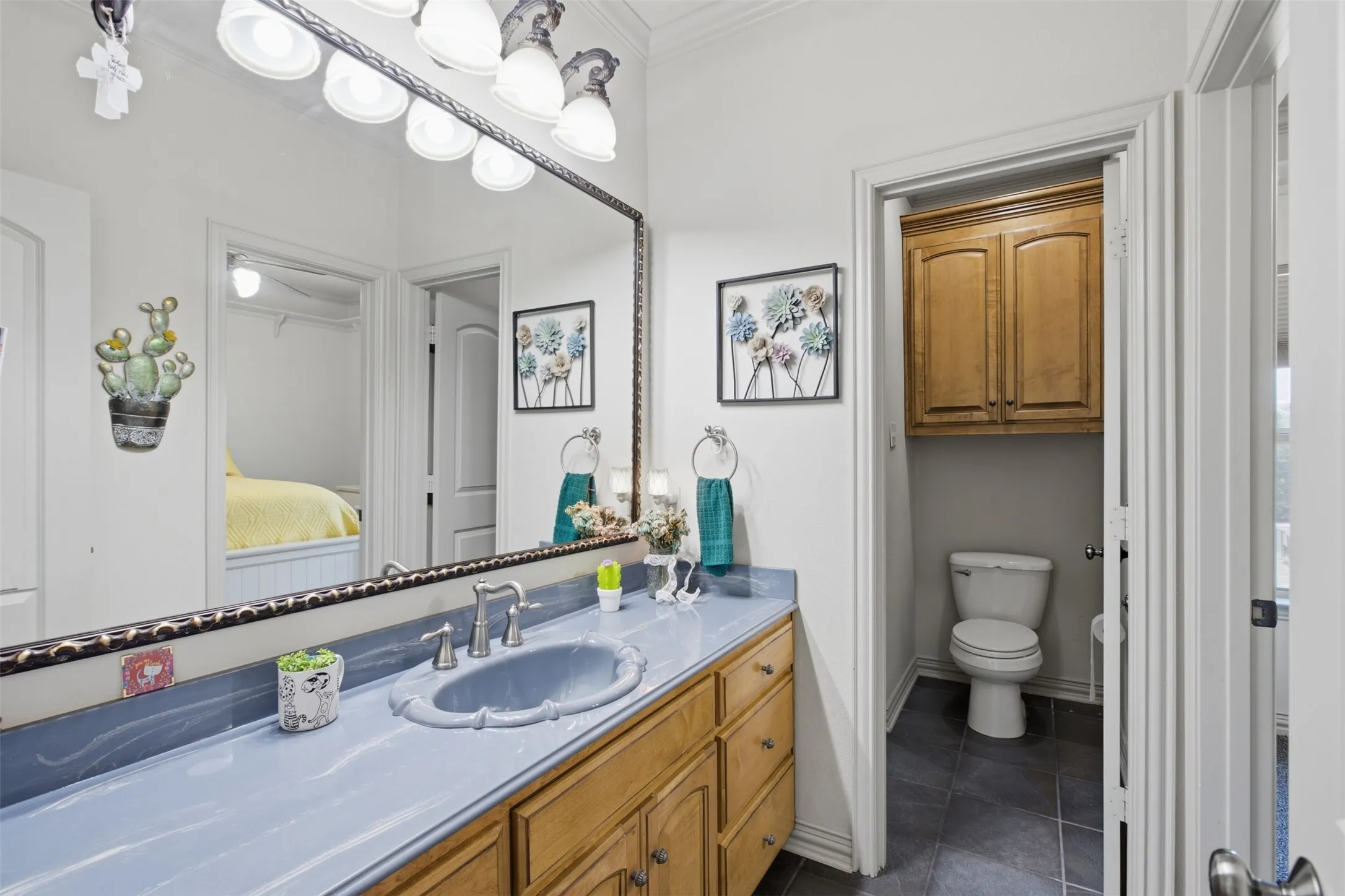 Vanity with an integrated basin, wood-finish cabinetry, and a large mirror with overhead lighting